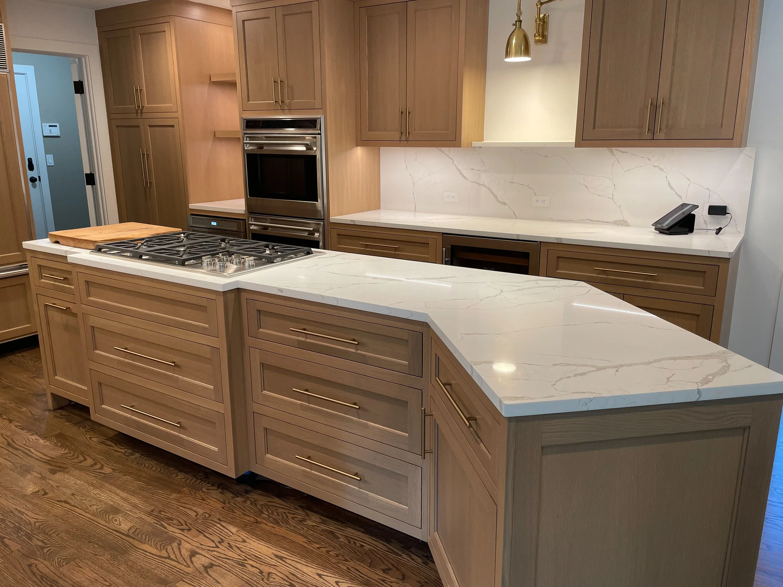 Inset white oak kitchen with quartz countertops and brass hardware 