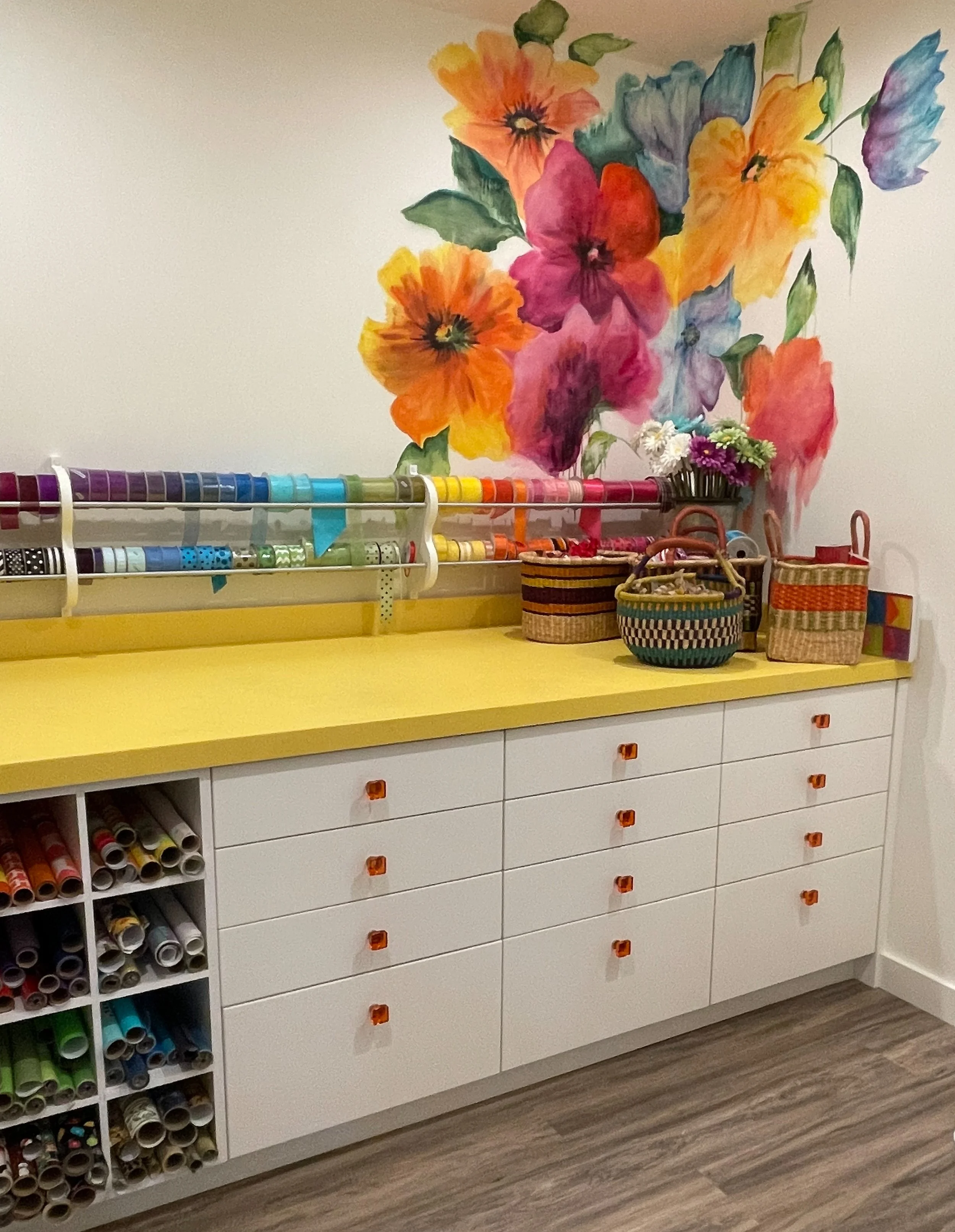White craft room with yellow countertops, floral wallpaper and custom ribbon and wrapping paper storage 