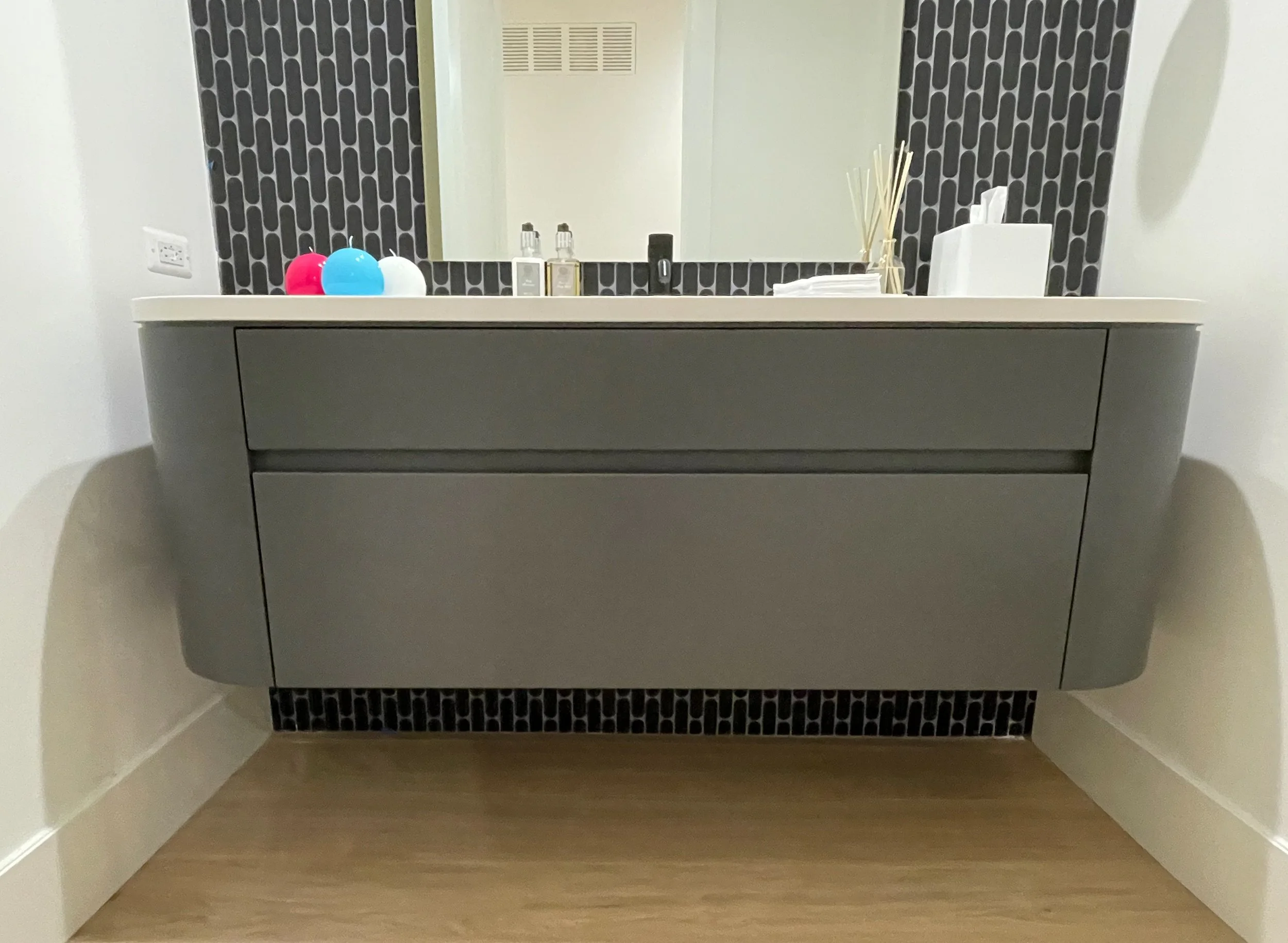 Custom floating grey vanity with curved sides and drawers with integrated pulls 