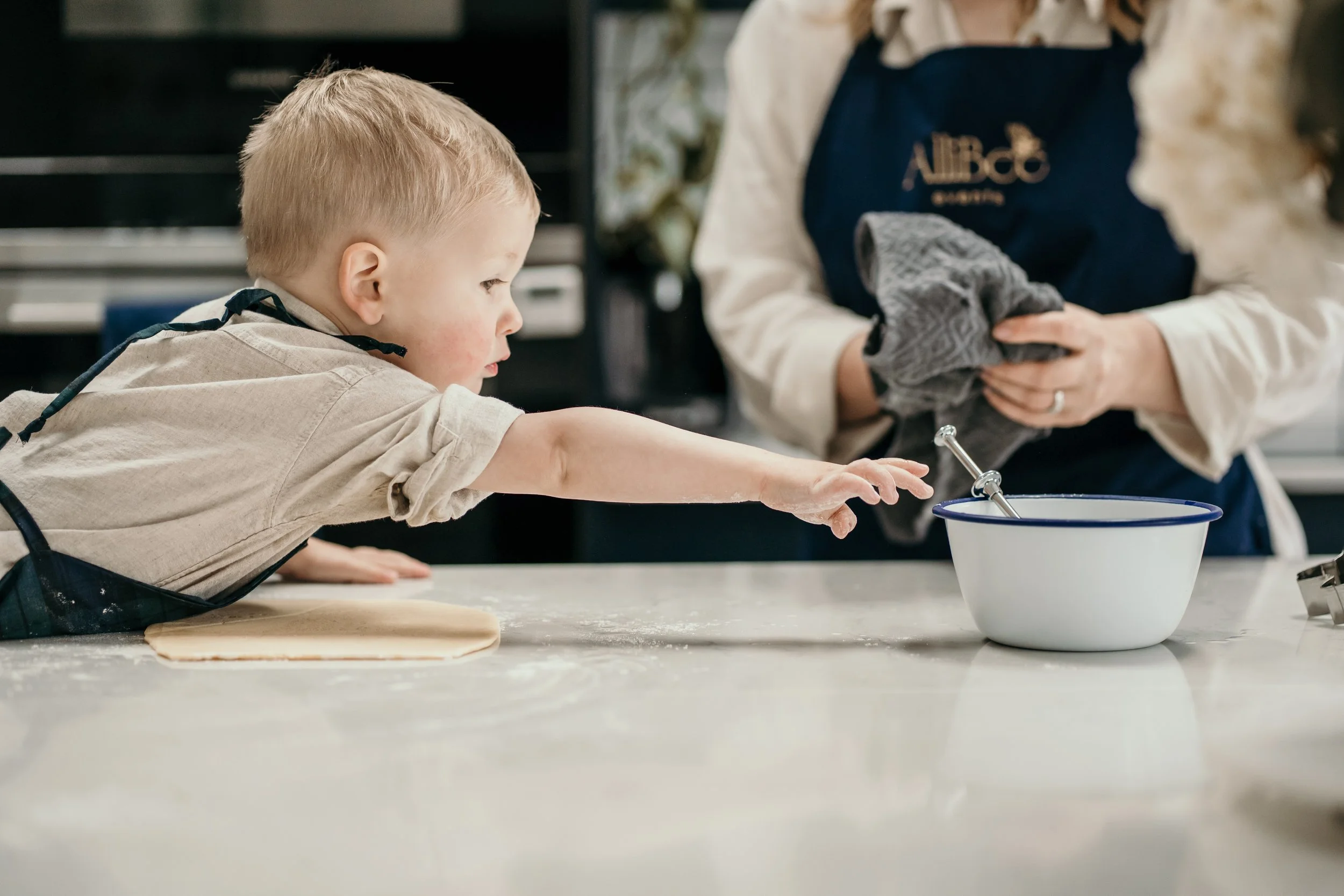 Child baking with mum at a kitchen counter.