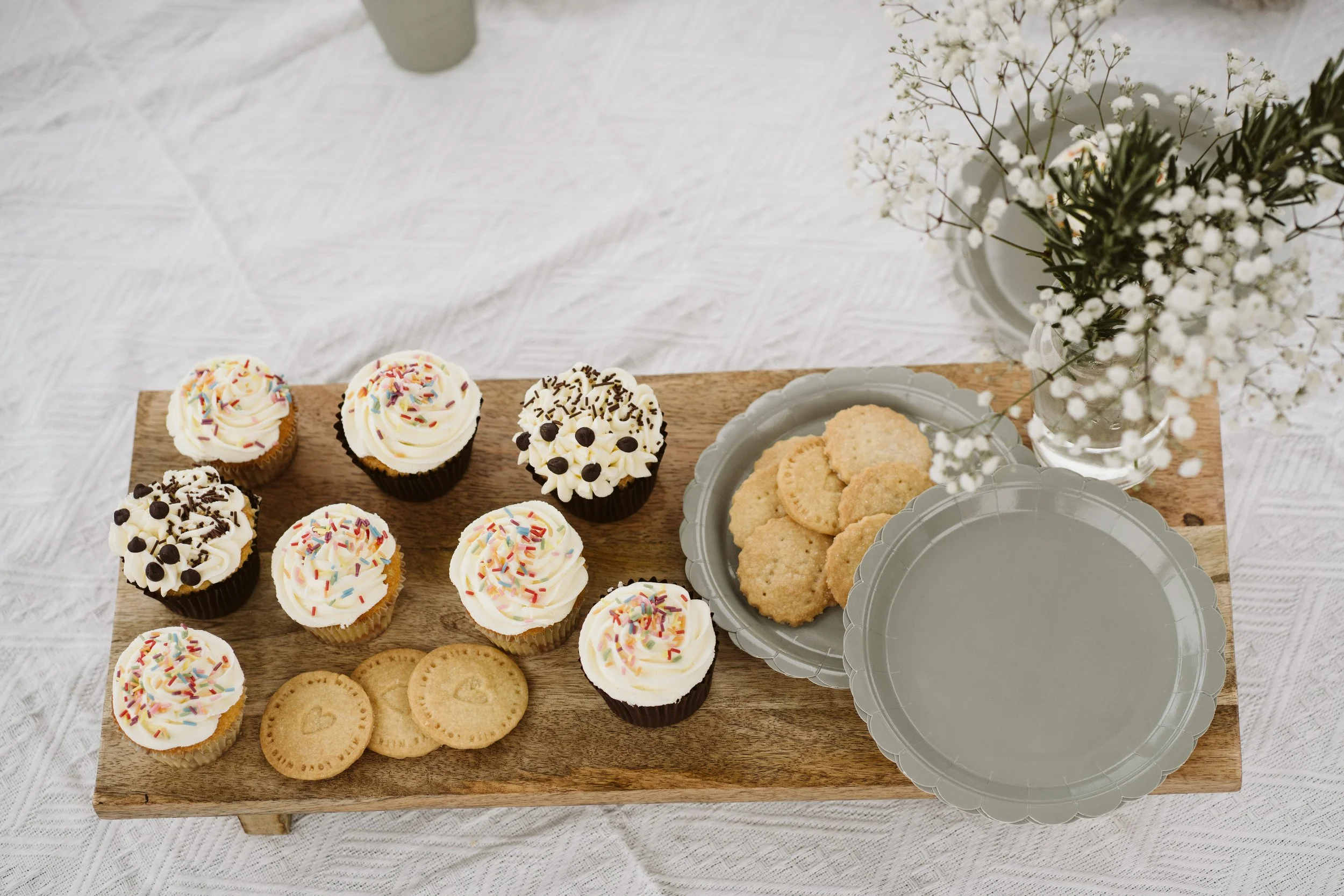 Decorated cupcakes and homemade cookies on a serving tray.