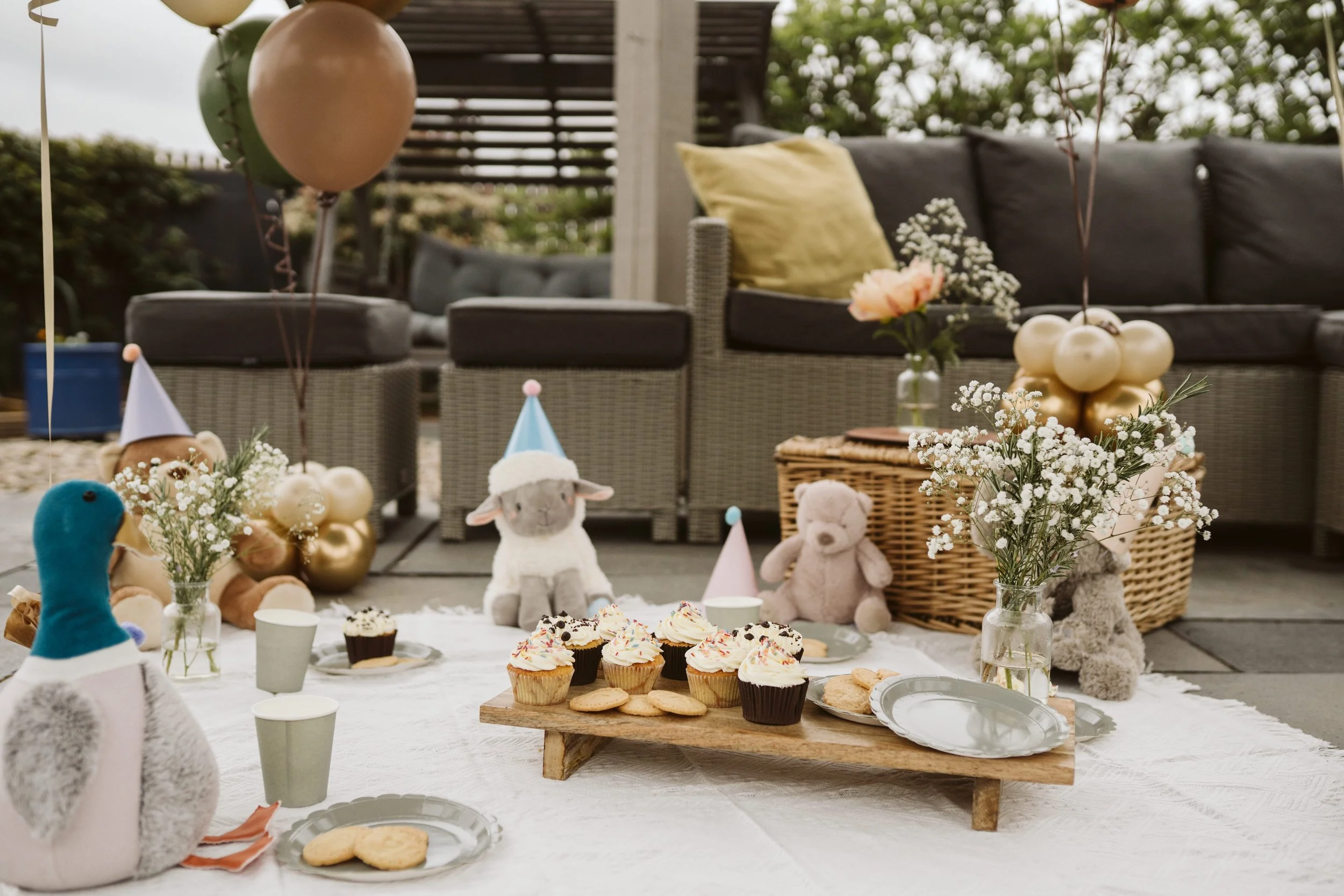 Outdoor children’s teddy bears picnic party table decorated with balloons and treats.