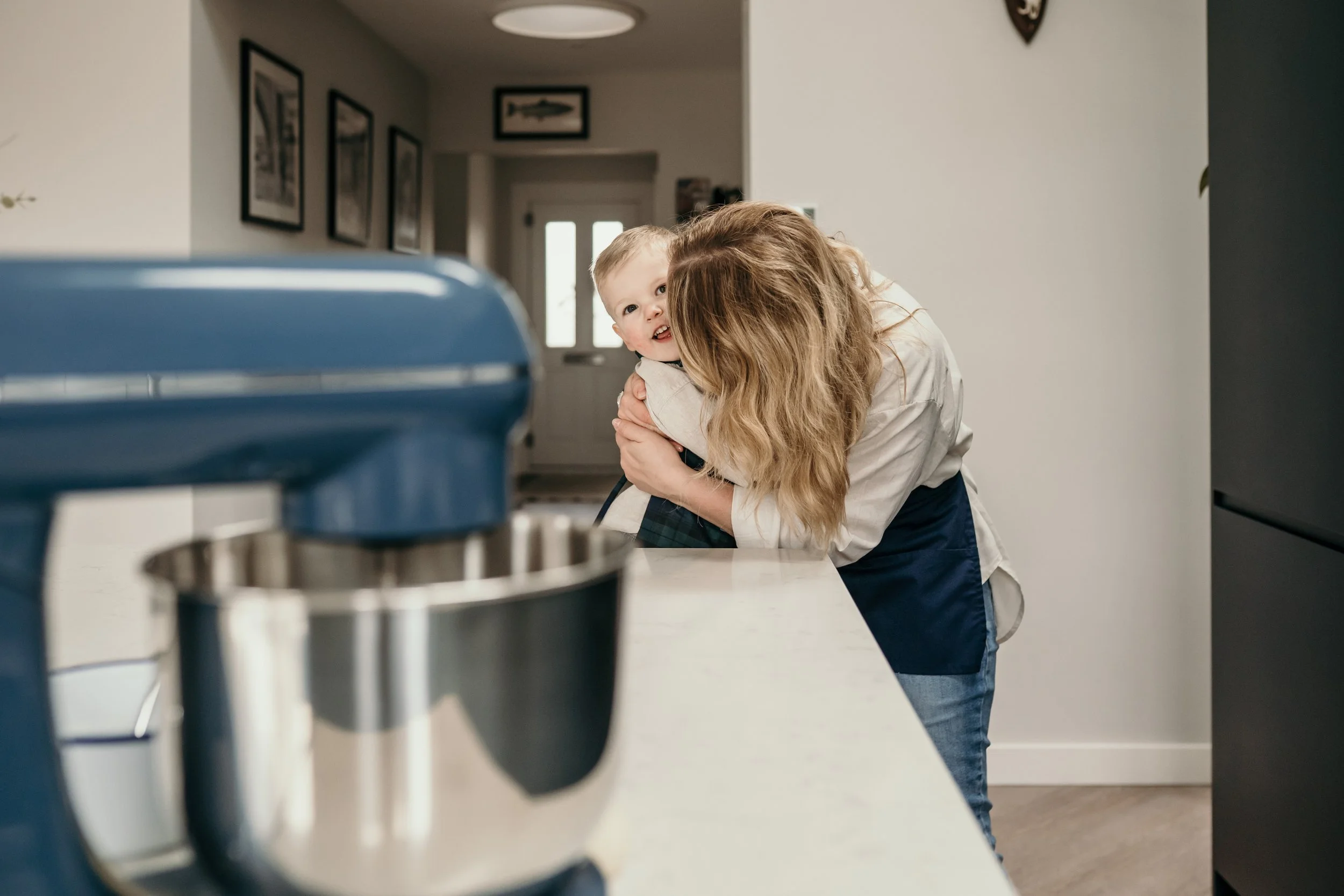 Mum using a stand mixer while baking with her child.