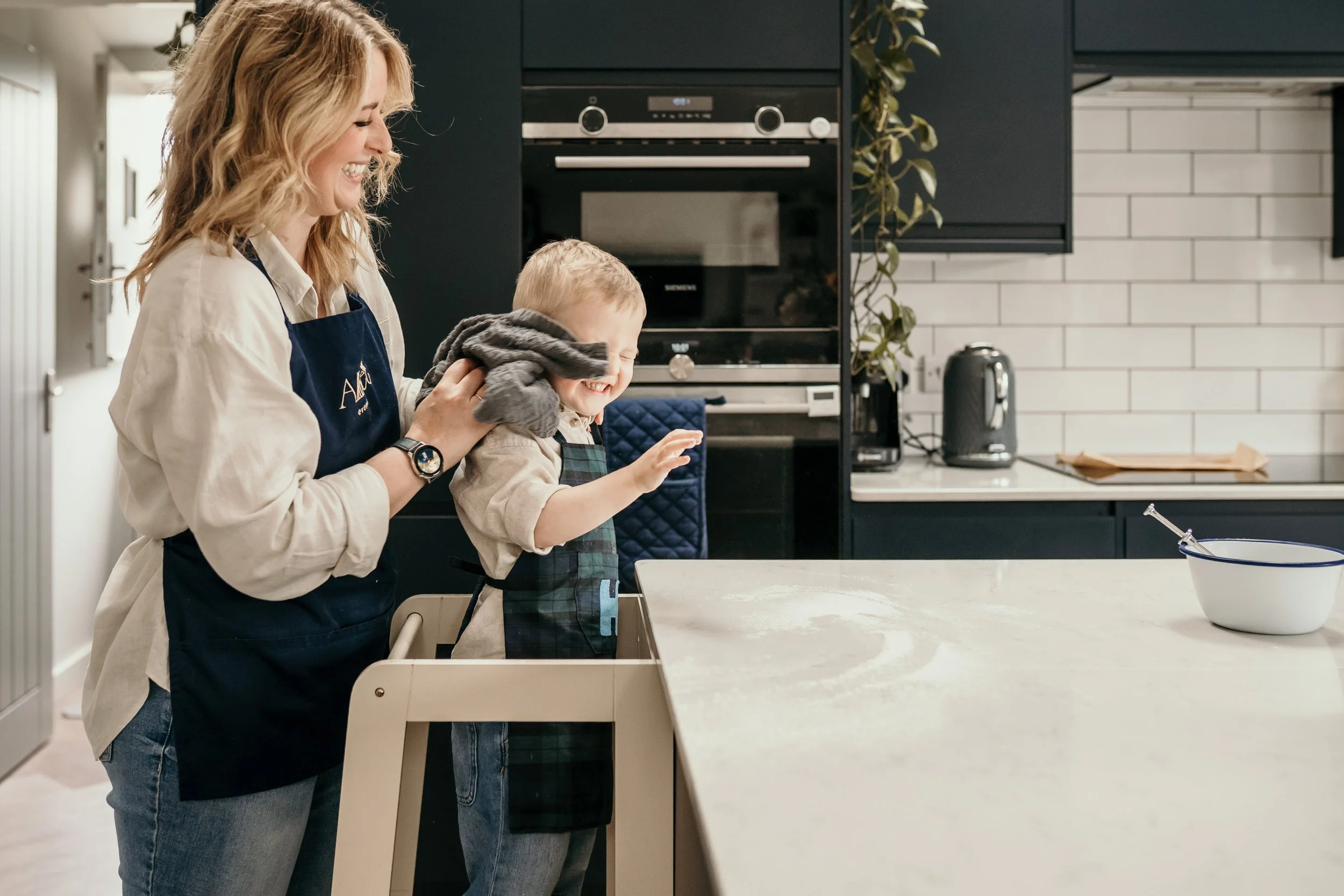 Mum helping child decorate cookies in the kitchen.