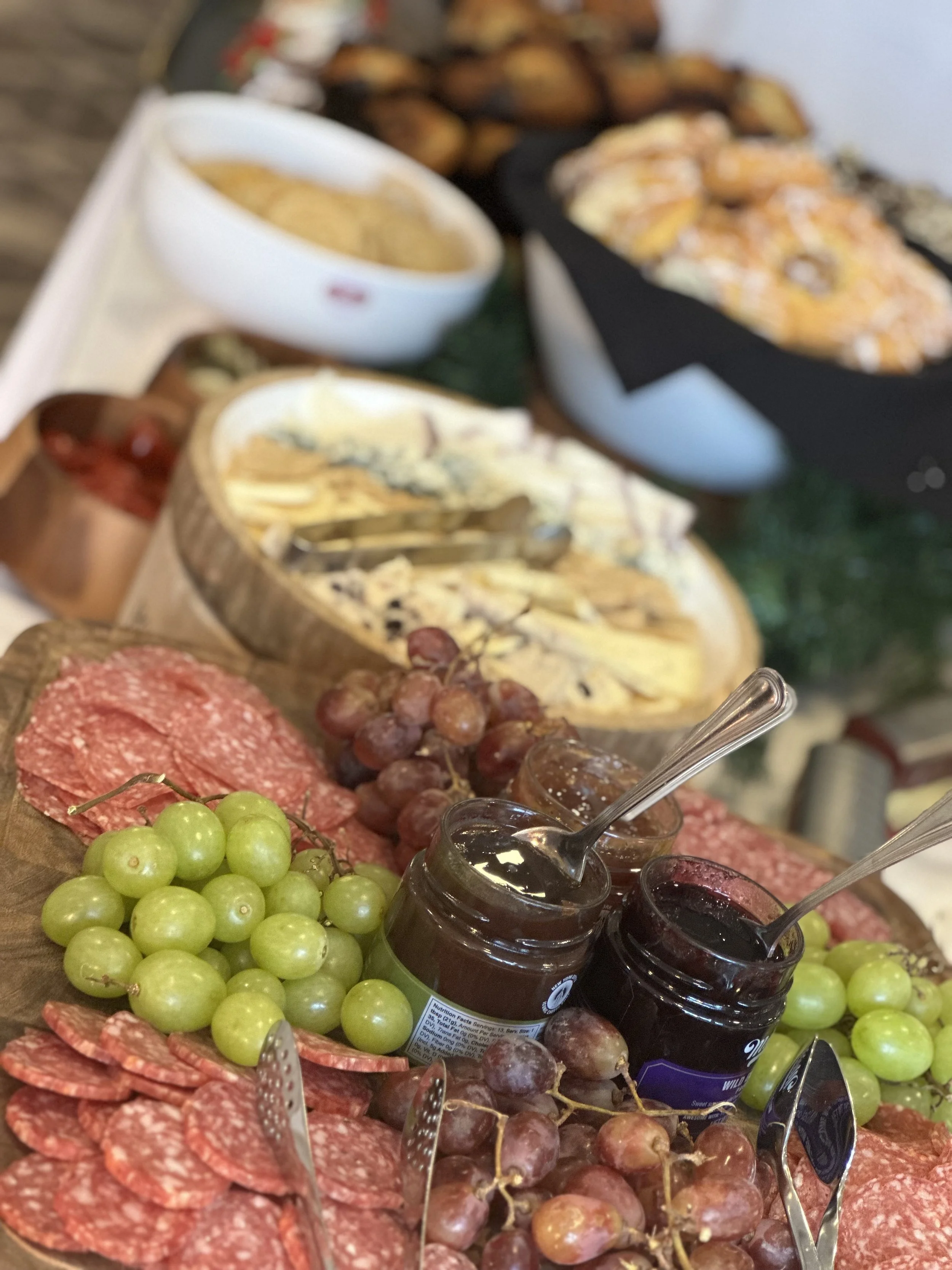 Assorted cheeses, grapes, salami, jams, and crackers on a charcuterie board.
