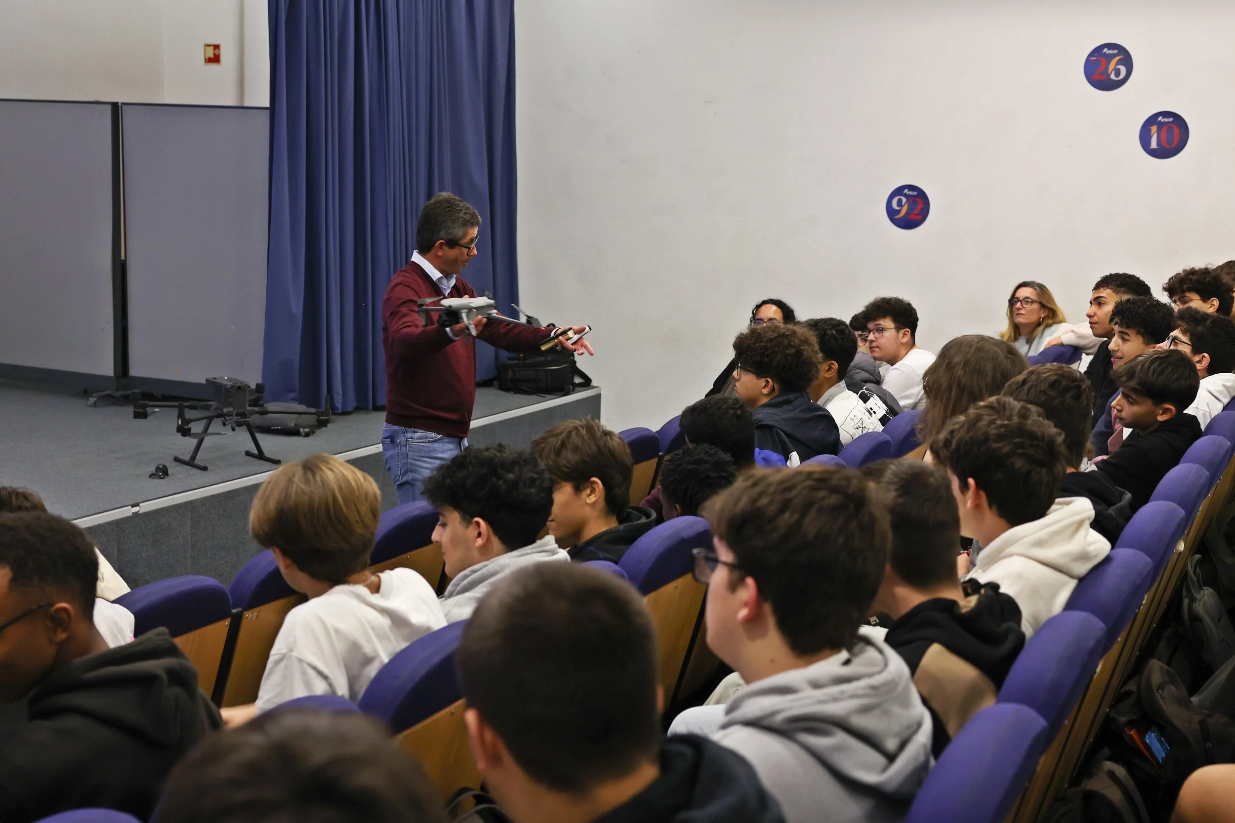 Professor demonstrando um drone para alunos em sala de aula.
