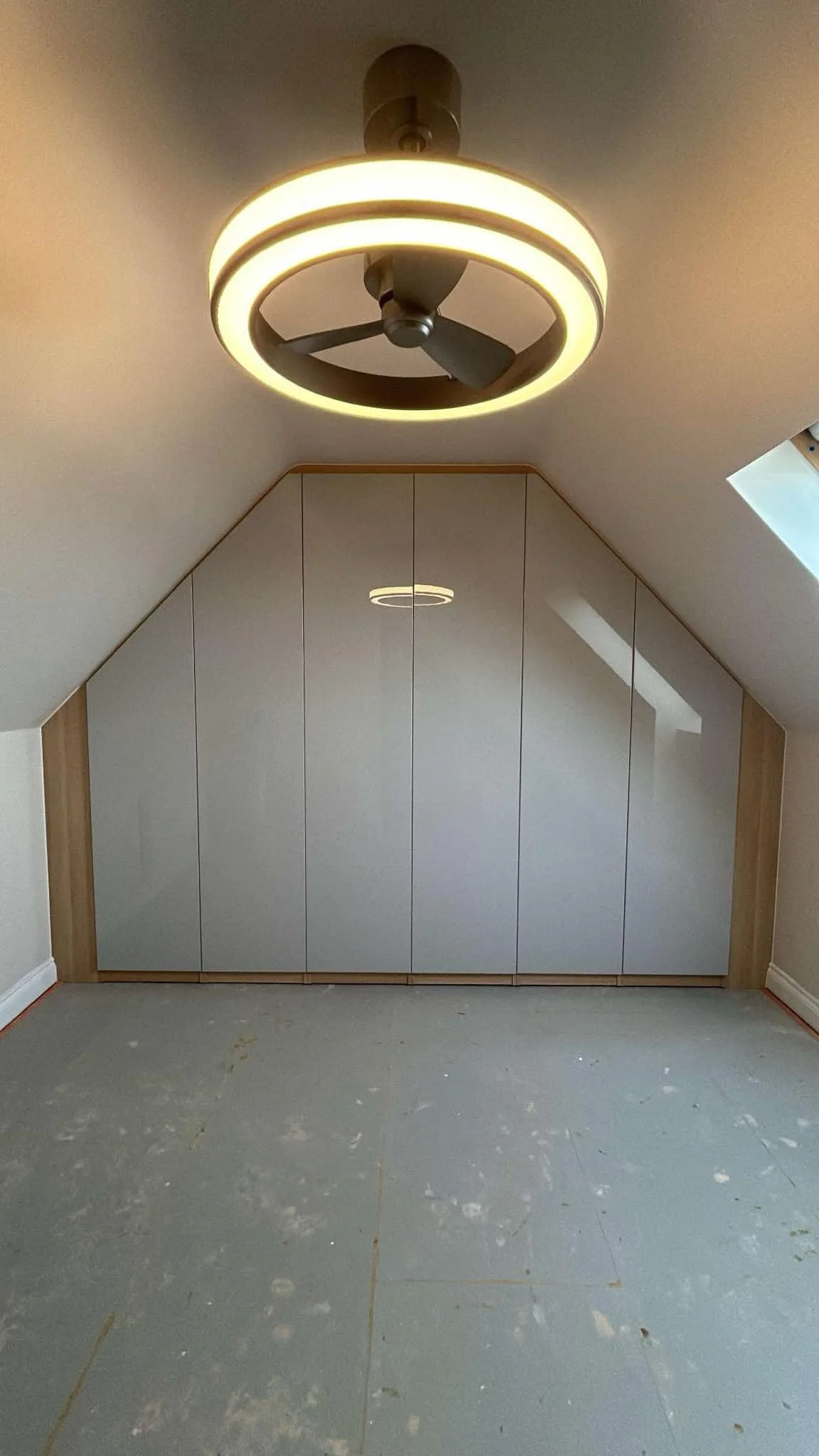 Room with sloped ceiling, built-in cabinet, and ceiling fan with light