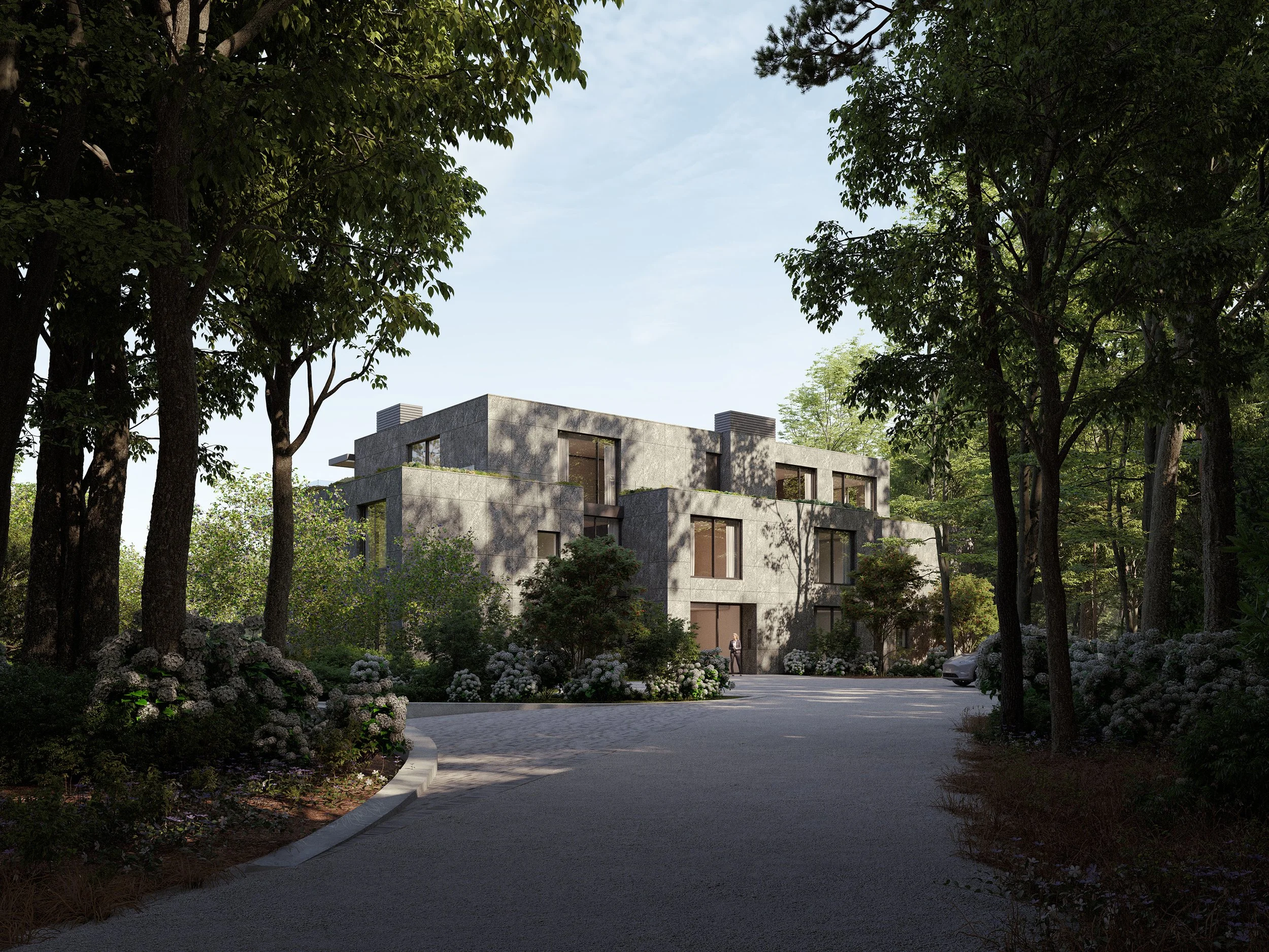 Modern multi-story residential building surrounded by tall trees and landscaping, with a paved driveway and a person walking near the entrance.