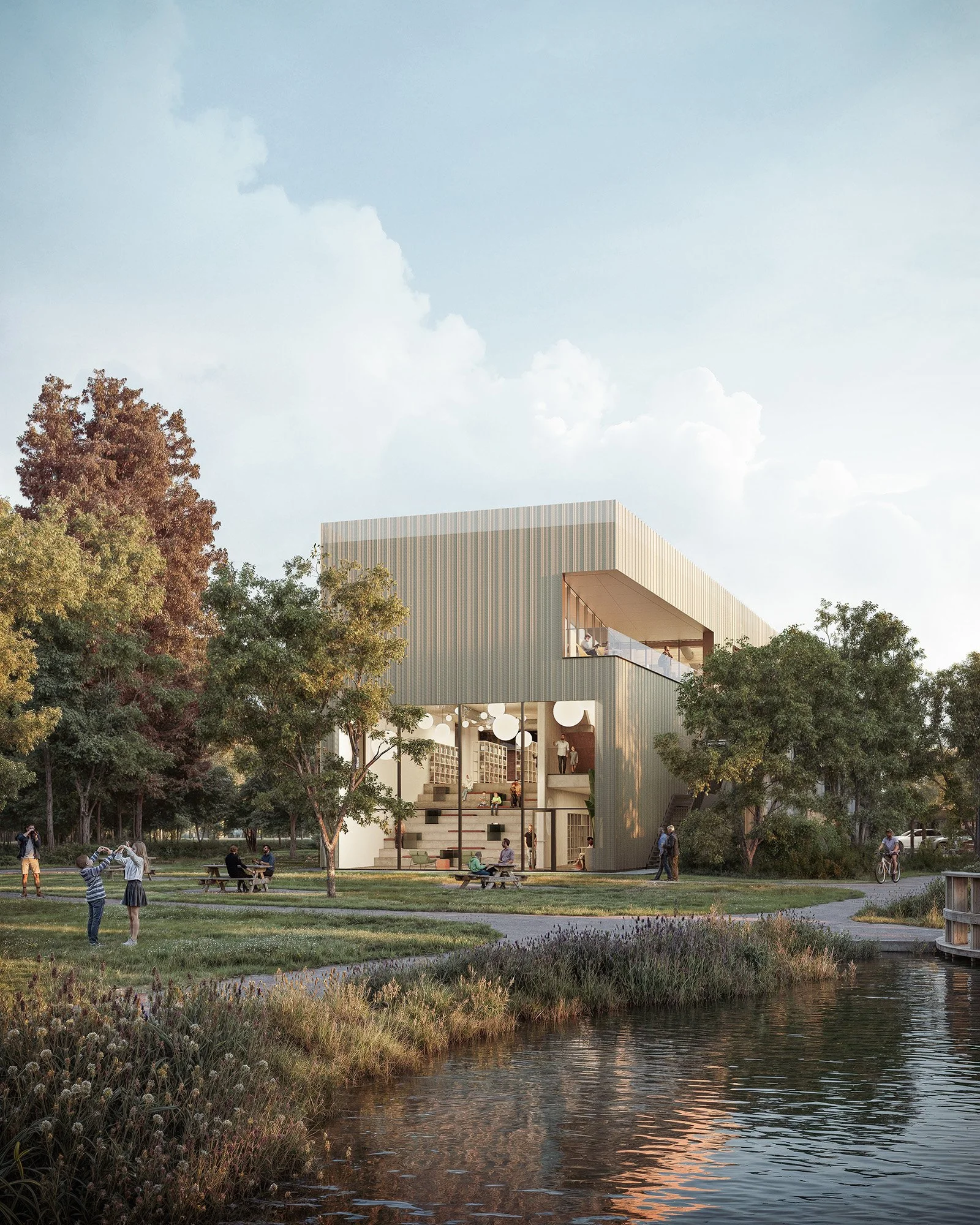 A modern multi-story building with open spaces, surrounded by trees and a park with people walking, biking, and sitting by a pond.