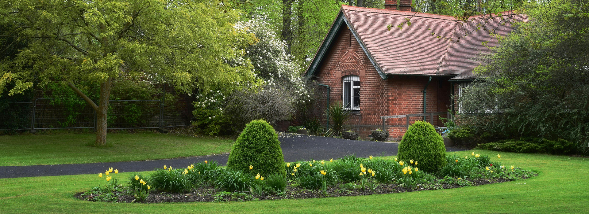 Lush green lawn and spring flowerbed in a traditional UK garden, representing the healthy Buckinghamshire lawn possible with proper establishment and maintenance
