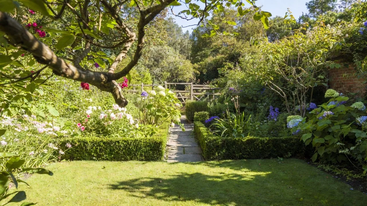 Berkshire garden with a stone path, clipped hedging and colourful planting