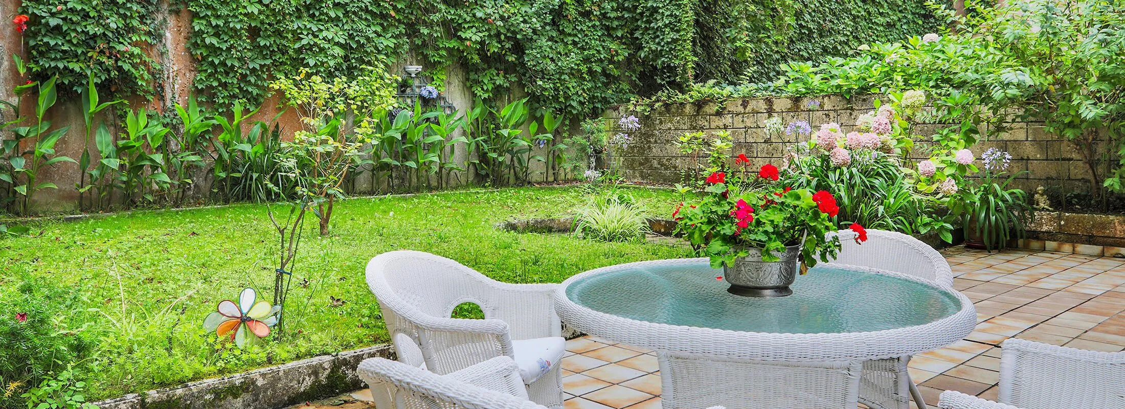 Private garden seating area screened by a wall of climbing plants and layered boundary planting.