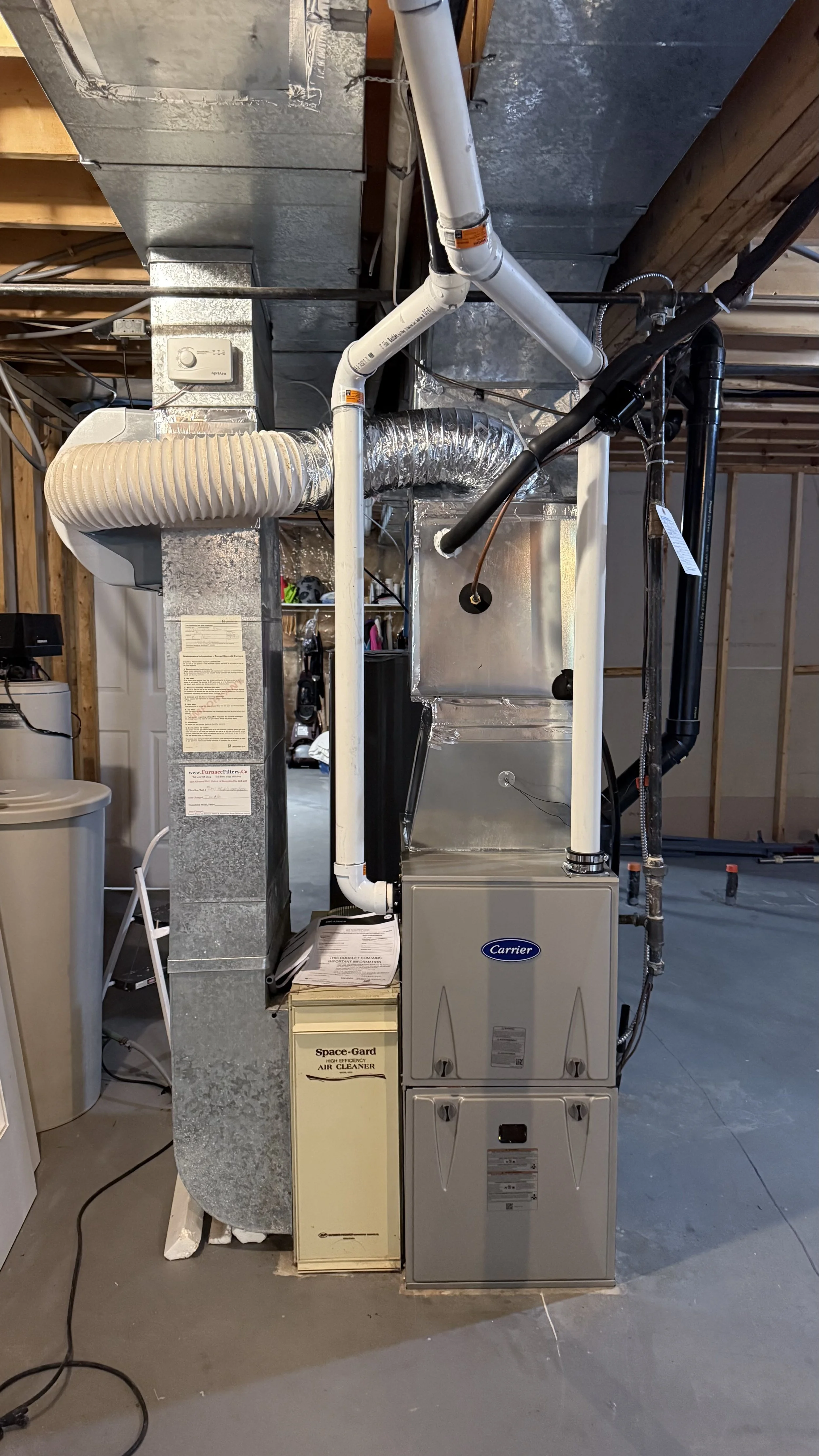 View of a home's HVAC system with ductwork, pipes, and a furnace in a basement under construction.