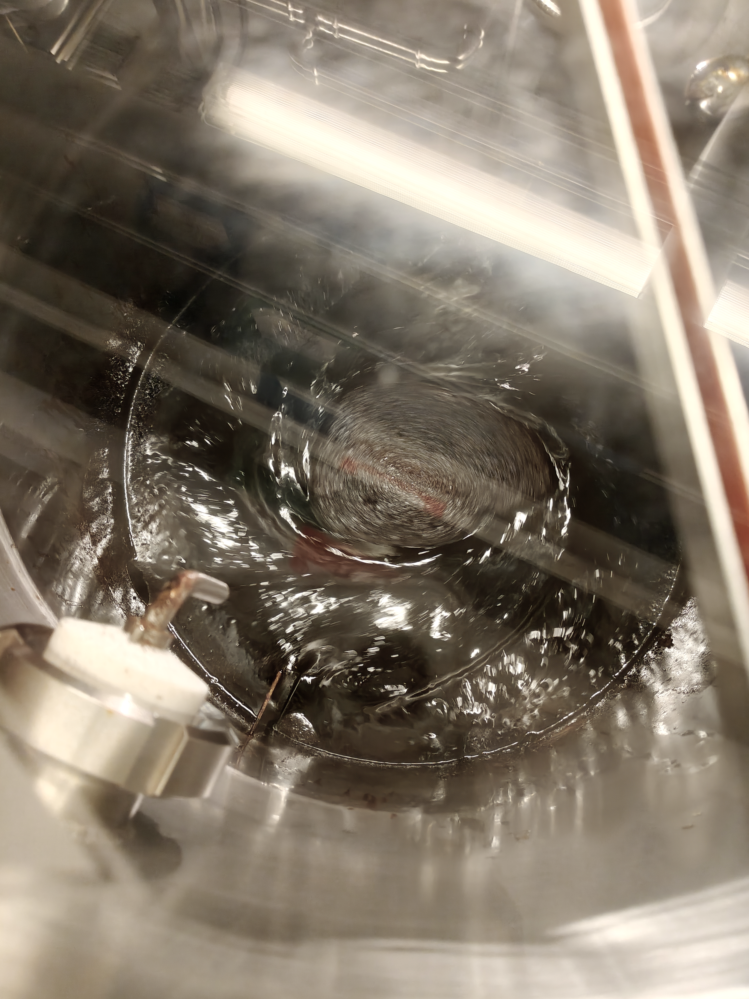 Looking inside a lignin liquid production while it is swirling at the bottom of a stainless steel mixer.