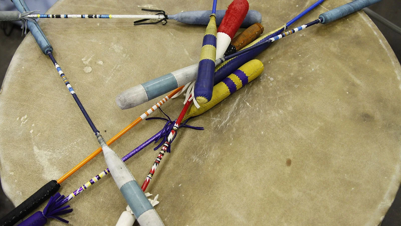 A collection of colorful, decorated fireworks or sparklers lying on a beige surface.