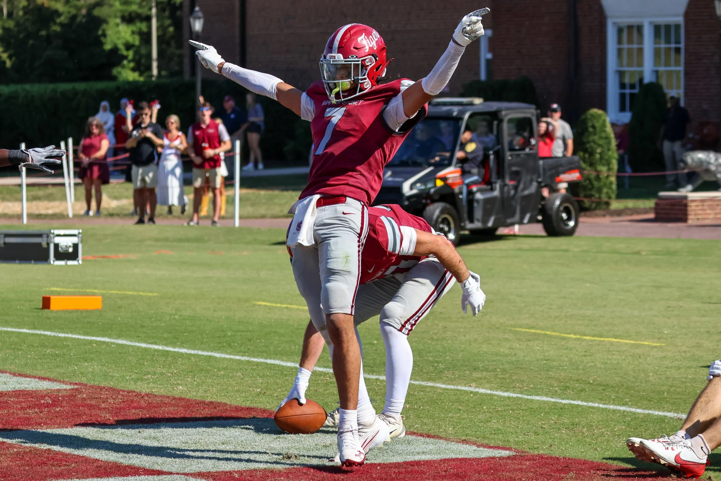American football player celebrating with arms raised after scoring a touchdown on the field.