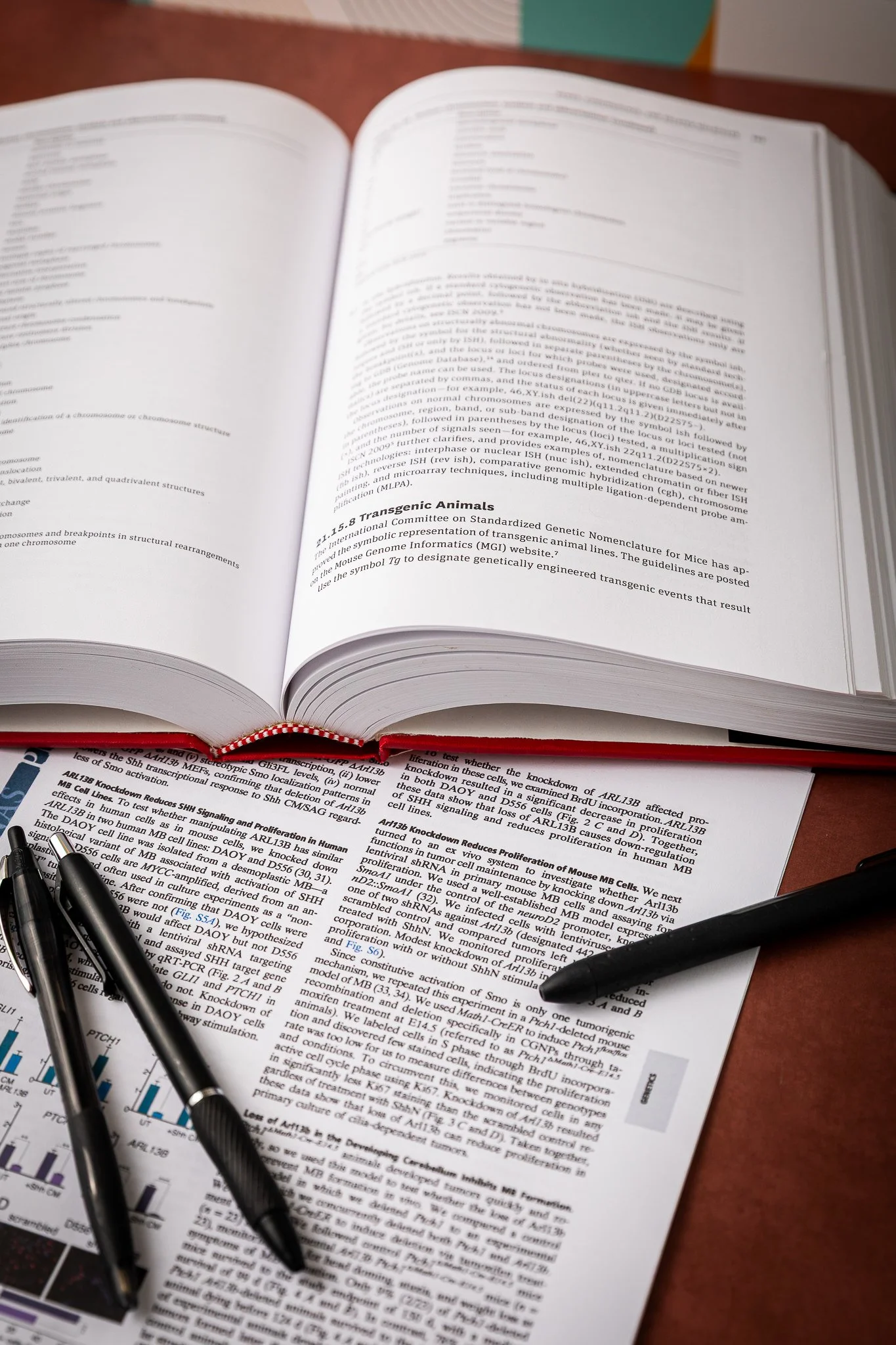 Pens lying on a scientific research paper with the Scientific Style and Format manual open nearby.