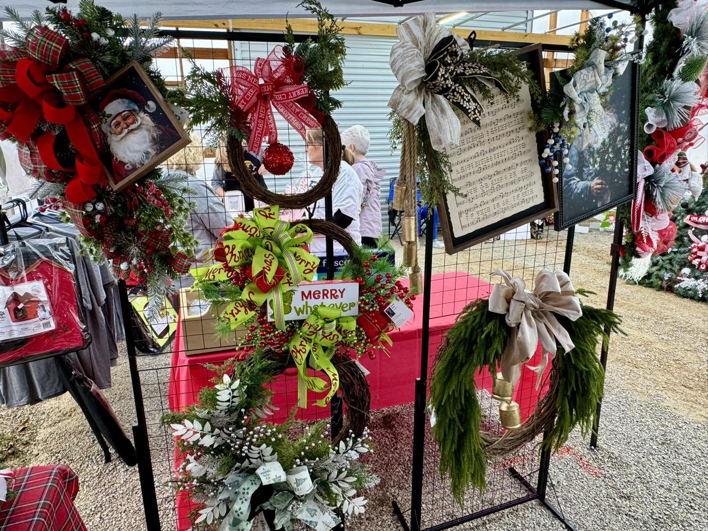 Christmas wreaths, ornaments, and holiday decorations displayed at an outdoor market stand.