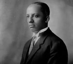 A young man dressed in a suit with a tie, posing for a formal black and white portrait.