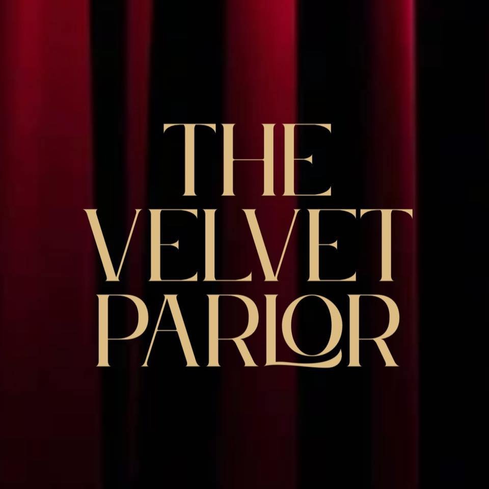 The words 'The Velvet Parlor' in large beige letters on a dark background with red curtain-like drapes.