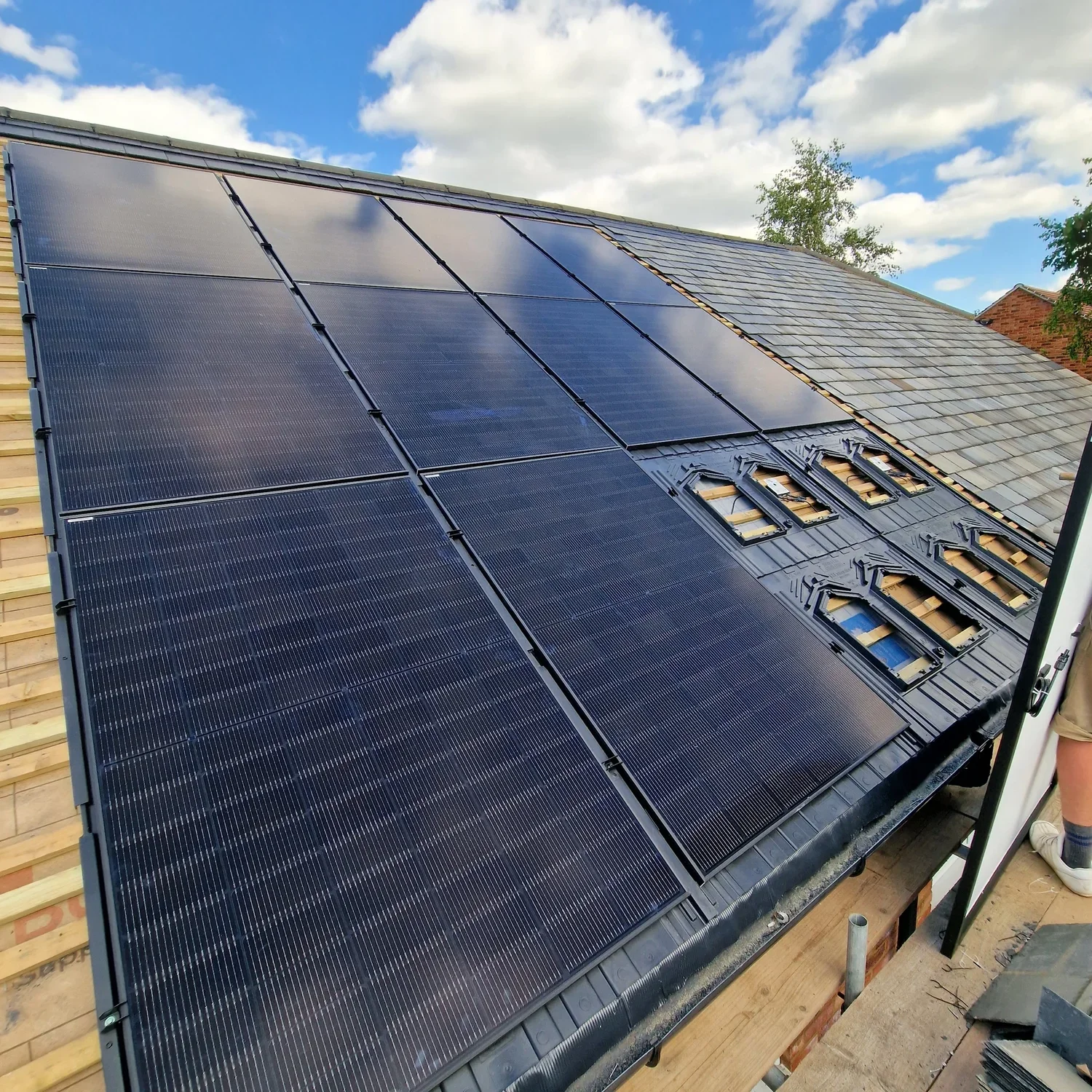 Solar panels installed on a sloped roof under a cloudy sky.