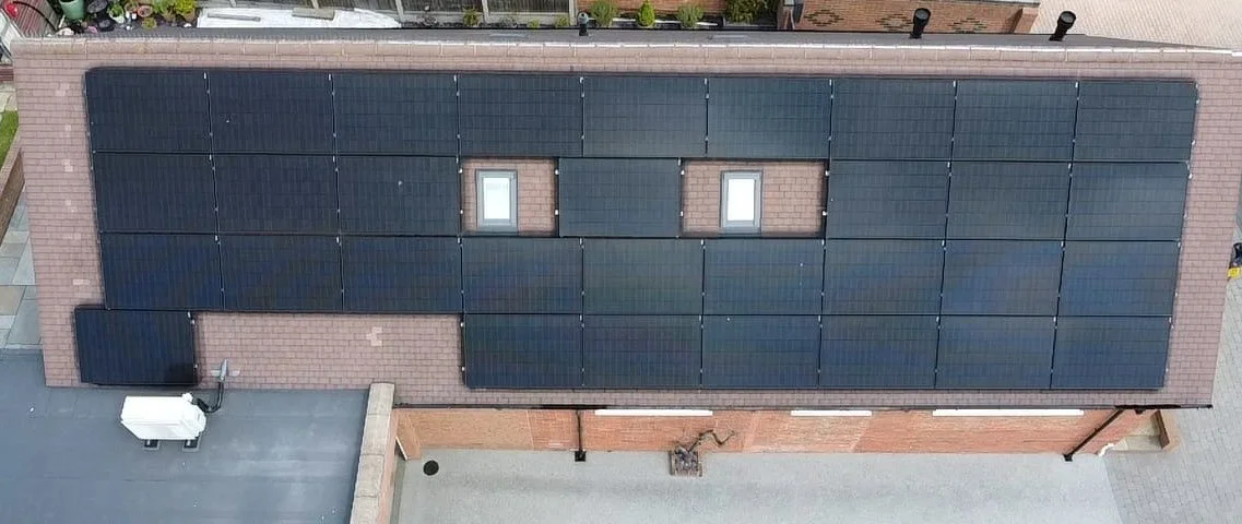 Aerial view of a building with multiple solar panels on the roof.