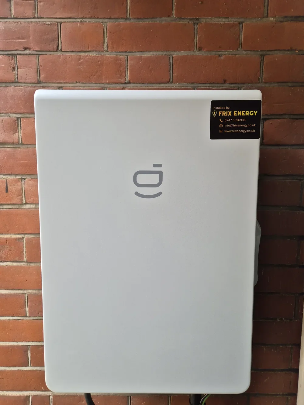 White electrical panel box mounted on a red brick wall, with a black and yellow sticker in the top right corner indicating installation by Frix Energy.