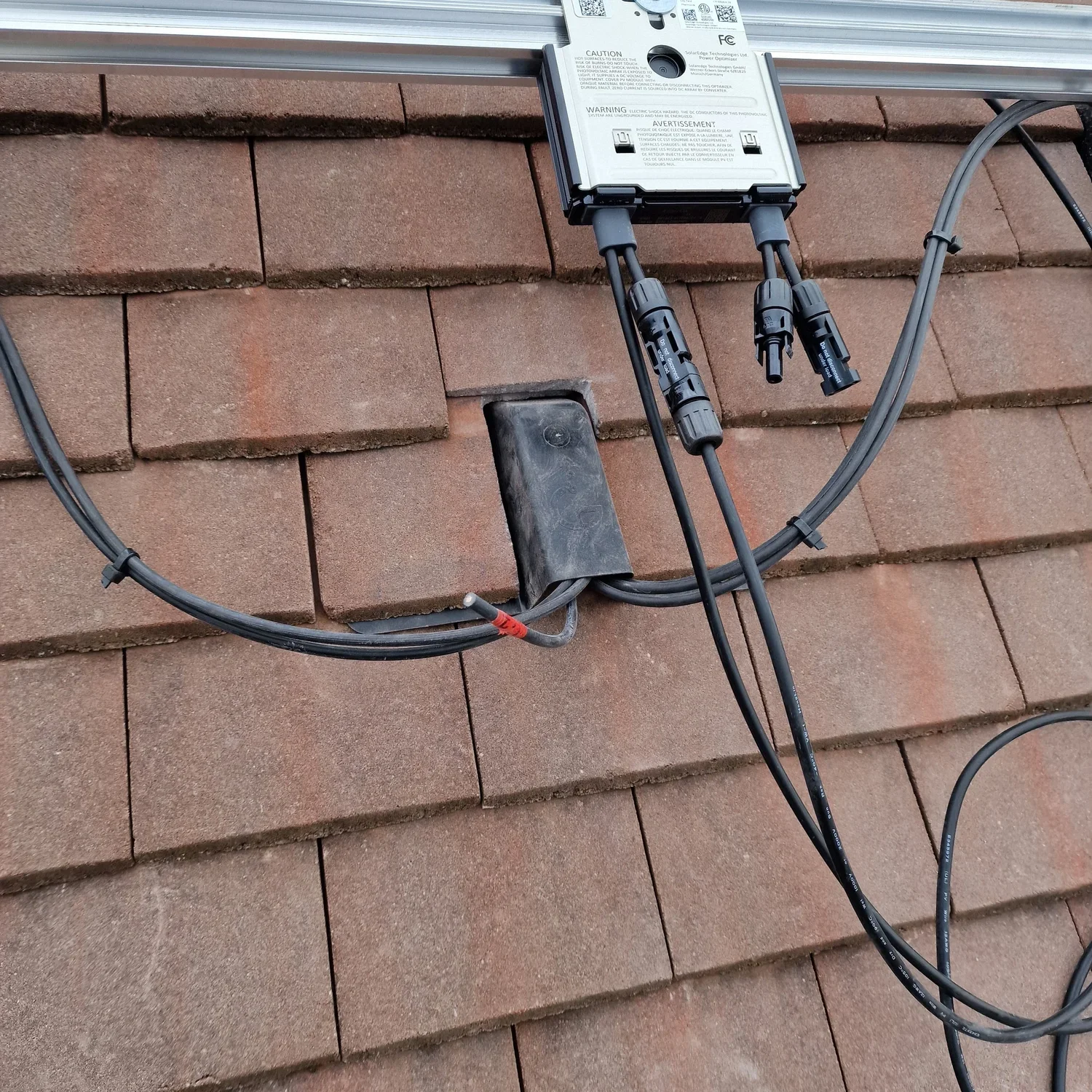 A solar power inverter mounted on a brick wall with connected electrical cables.