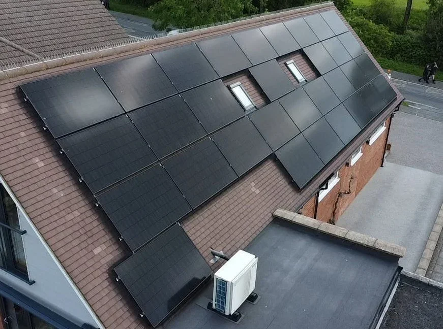 House roof with multiple black solar panels installed.