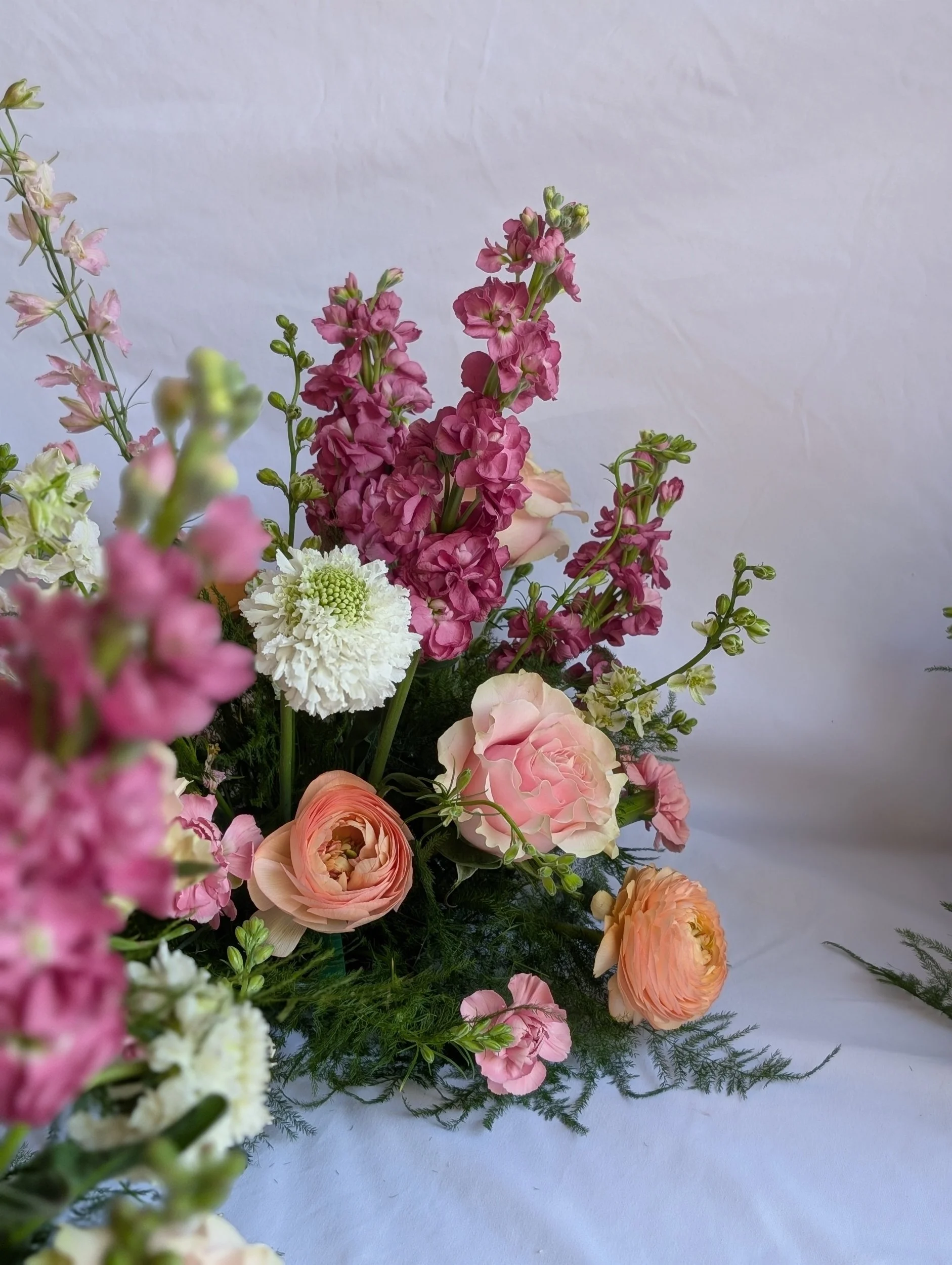 Arrangement of pink, peach, white, and green flowers against a white background.