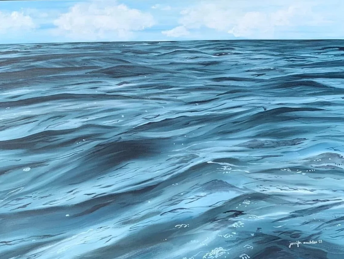 Close-up view of ocean water with gentle waves and a cloudy sky.