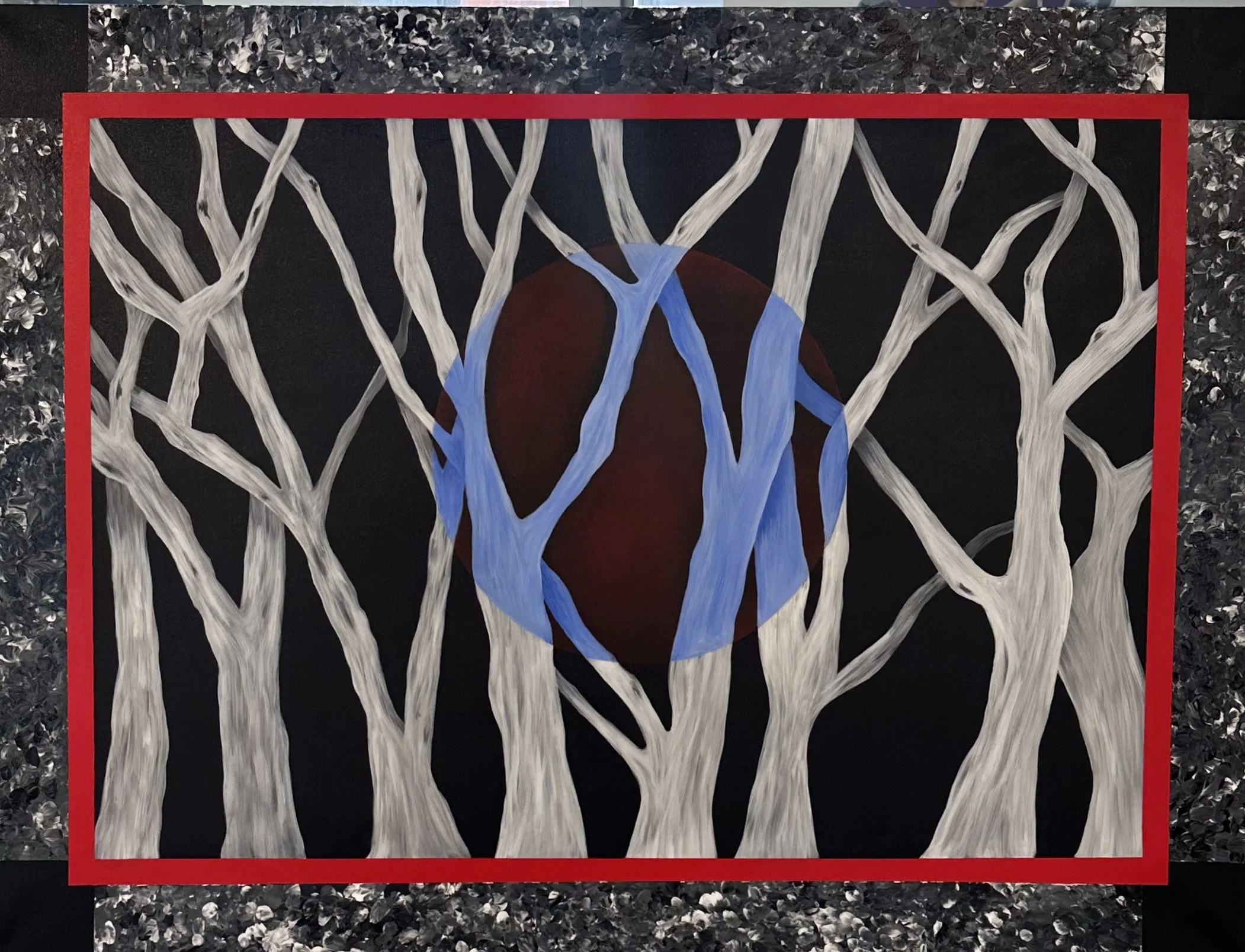 An abstract painting showing white tree branches on a black background with a dark red sphere and blue streaks in the center, framed with a red border and surrounded by black and silver textured material.