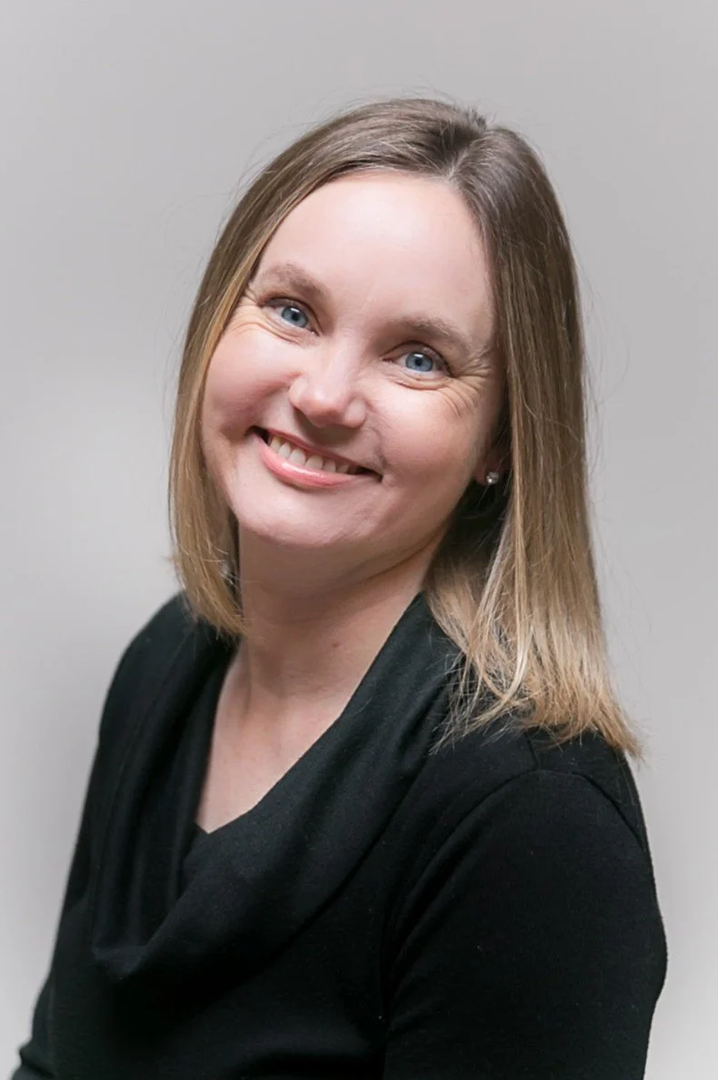 Irene Kraegel, PsyD offers Christian therapy in-person in East Grand Rapids, MI and online in 43 PsyPact states. Photo shows Dr. Kraegel smiling with blue eyes, light brown hair, small sparling earrings, and a black scoop-neck shirt.
