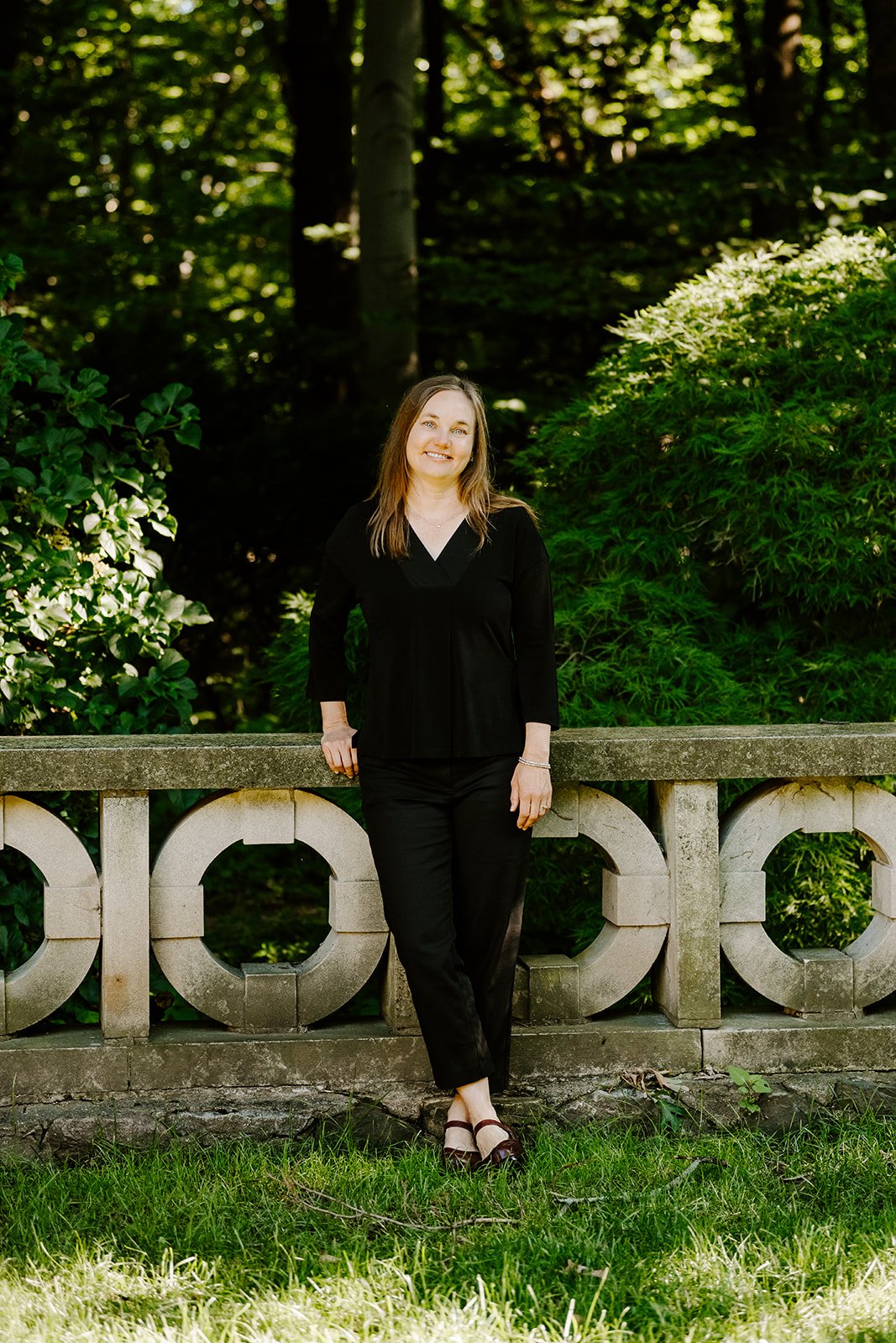 Psychologist Irene Kraegel leans against a stone wall. Dr. Kraegel provides Pain Reprocessing Therapy to ease chronic pain.