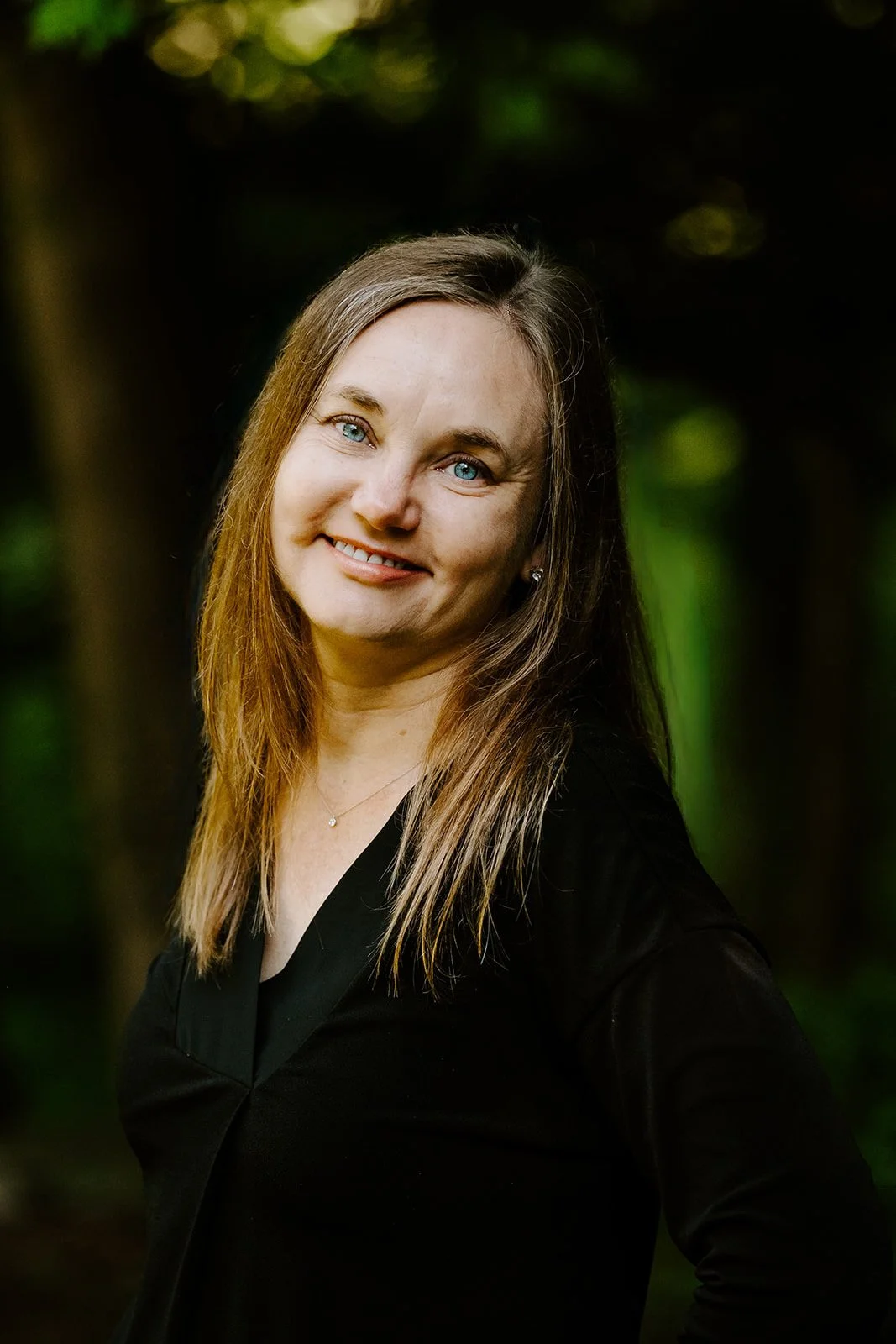 Dr. Irene Kraegel, PsyD, with light blonde hair and a black shirt stands with a wooded background. Dr. Kraegel provides Christian mindfulness coaching in Grand Rapids, MI, and virtually.