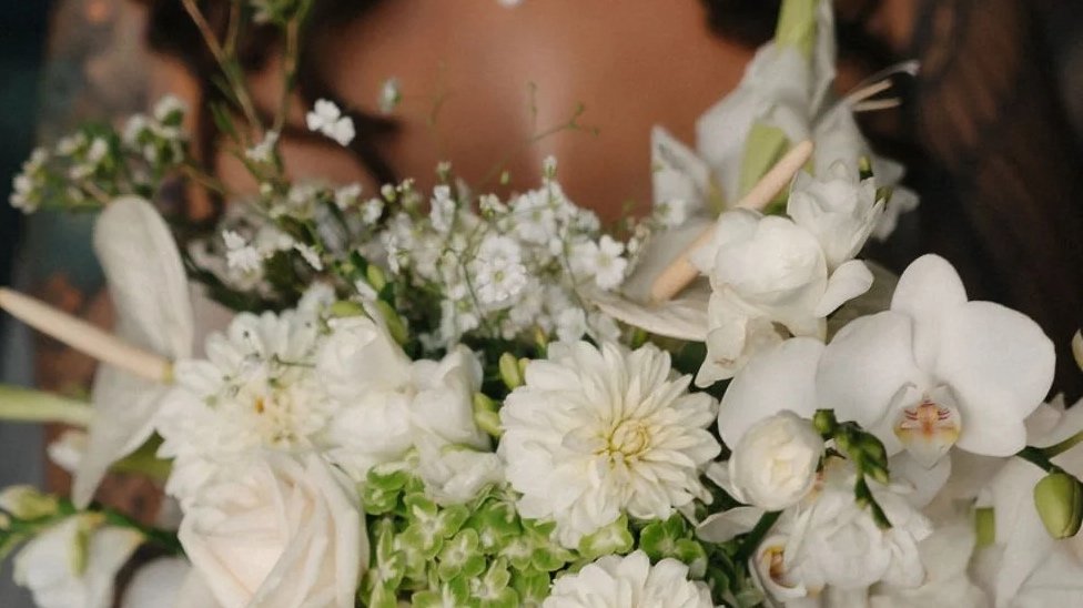 Close-up of a bouquet of white flowers including orchids, dahlias, and smaller filler flowers.