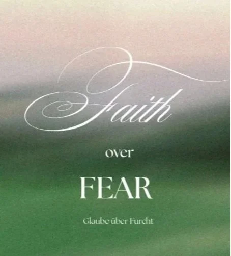 Inspirational quote saying "Faith over Fear" with German translation "Glaube über Furcht" on a blurred background.