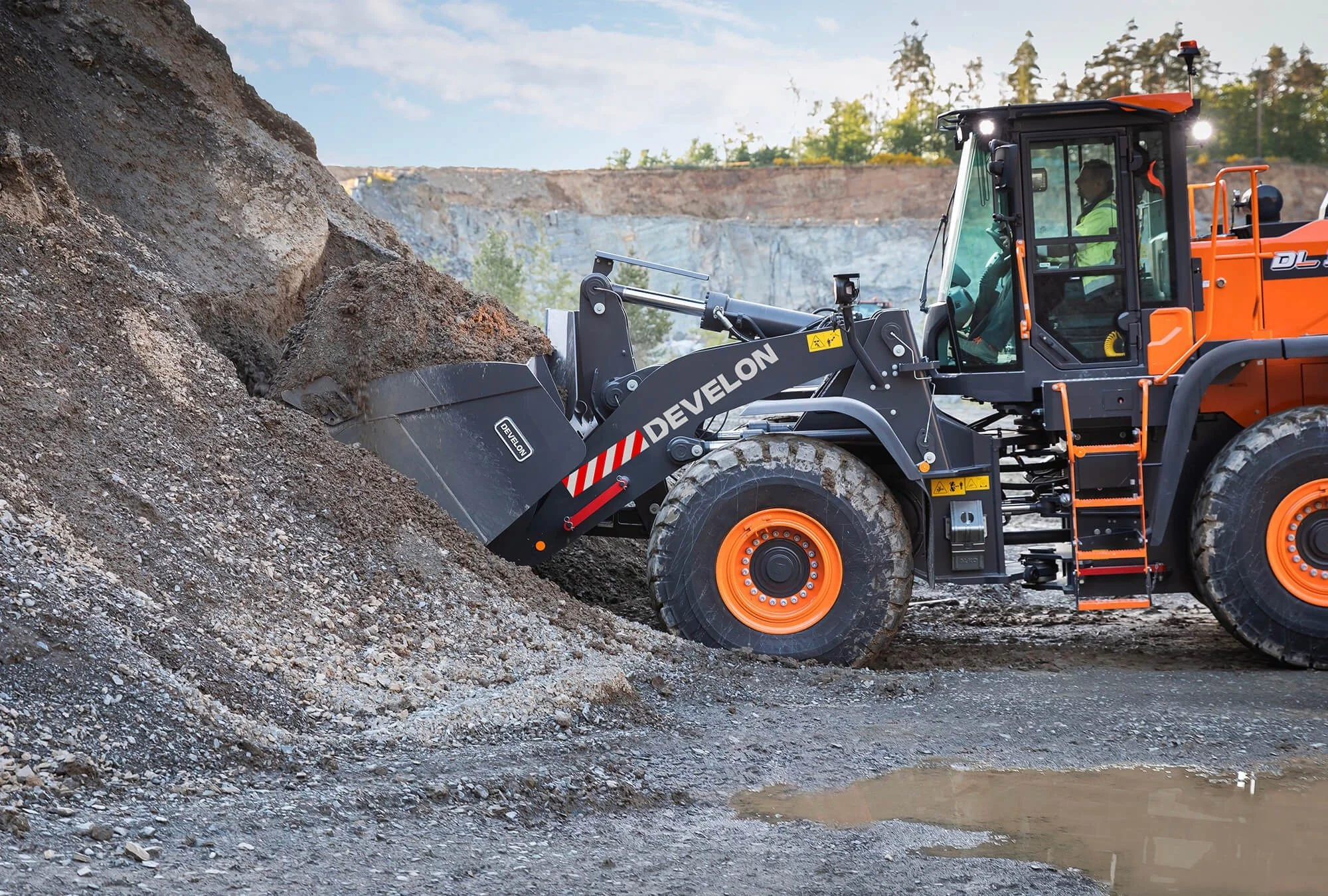 A large orange and black bulldozer moving dirt and rocks in a quarry or construction site.