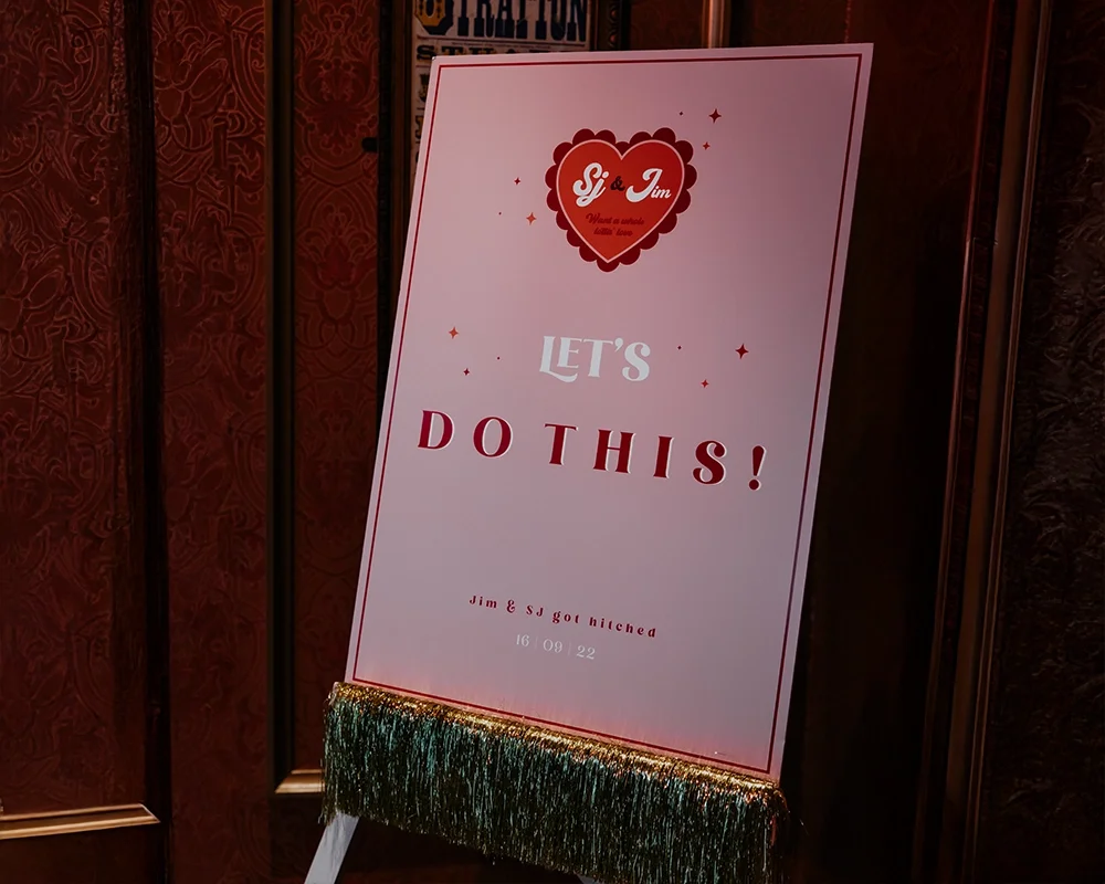 Wedding reception sign on an easel with romantic heart logo and the message 'Let's do this!'