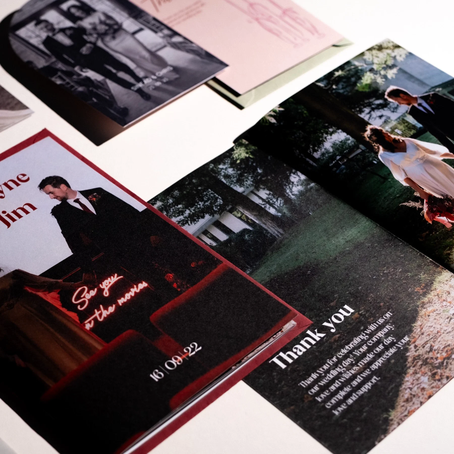 Wedding photo and thank you cards on a white table, including a picture of a groom in a black suit and a bride in a white dress outdoors.