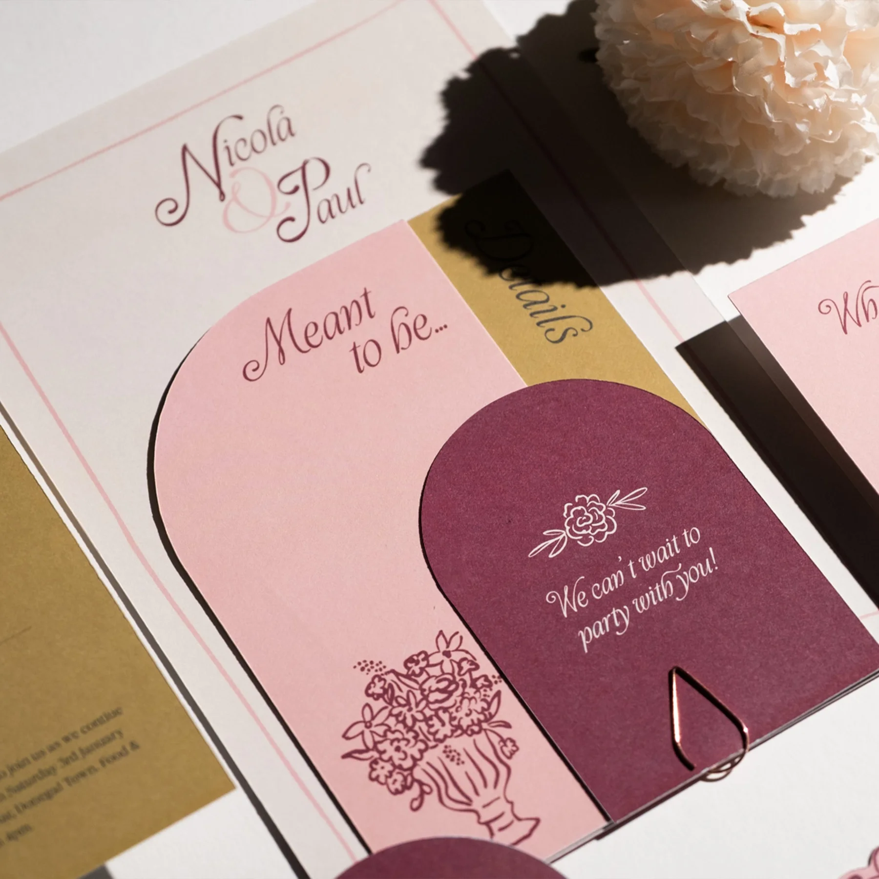 A colorful wedding program with the names Nicola and Paul and the phrases "Meant to be..." and "We can't wait to party with you!" along with floral illustrations and a white flower decoration.
