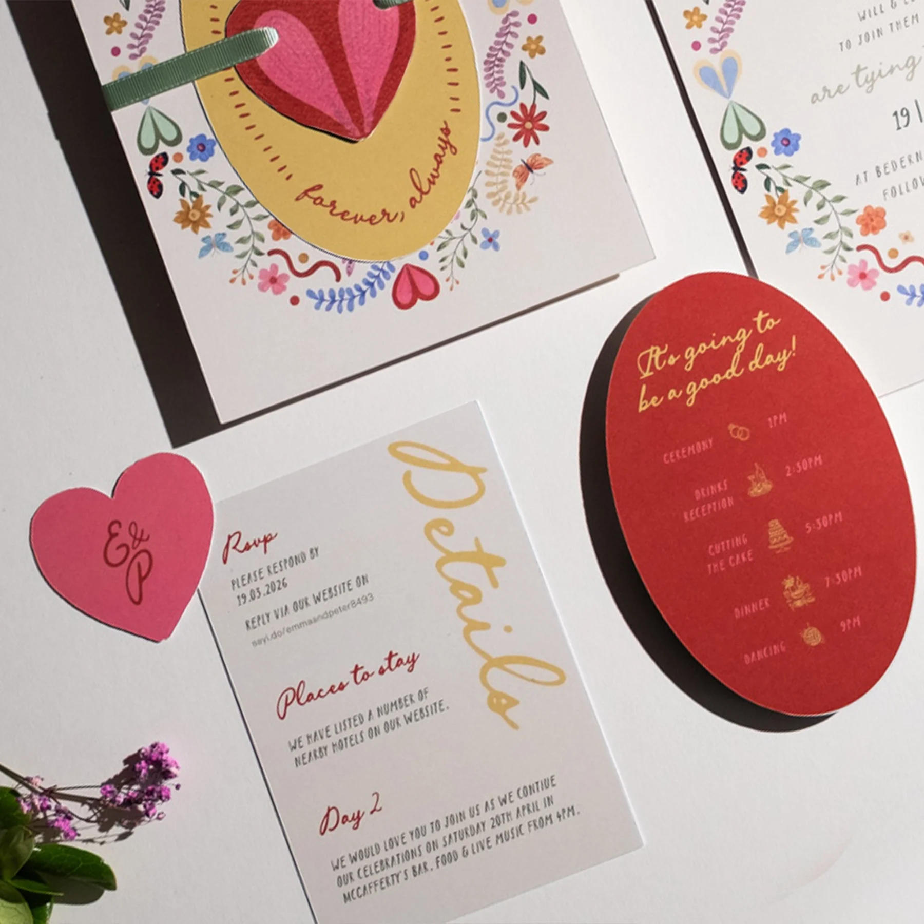 Wedding invitation and schedule cards with floral and heart motifs, including a red oval with events listed and a pink heart with the names E & P.