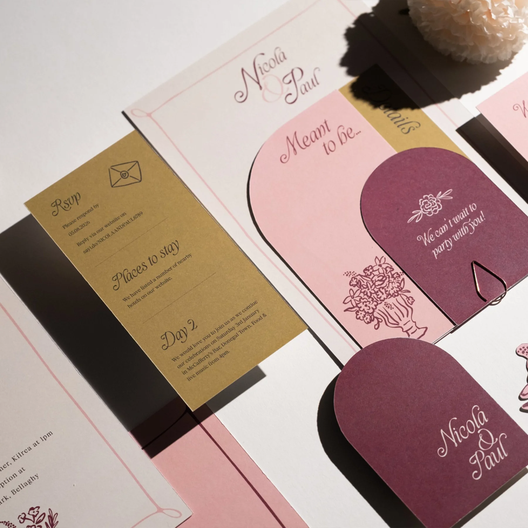Wedding invitation with pink and purple theme, floral designs, and the names Nicola and Paul. Includes a gold RSVP card and information about places to stay on Day 2.