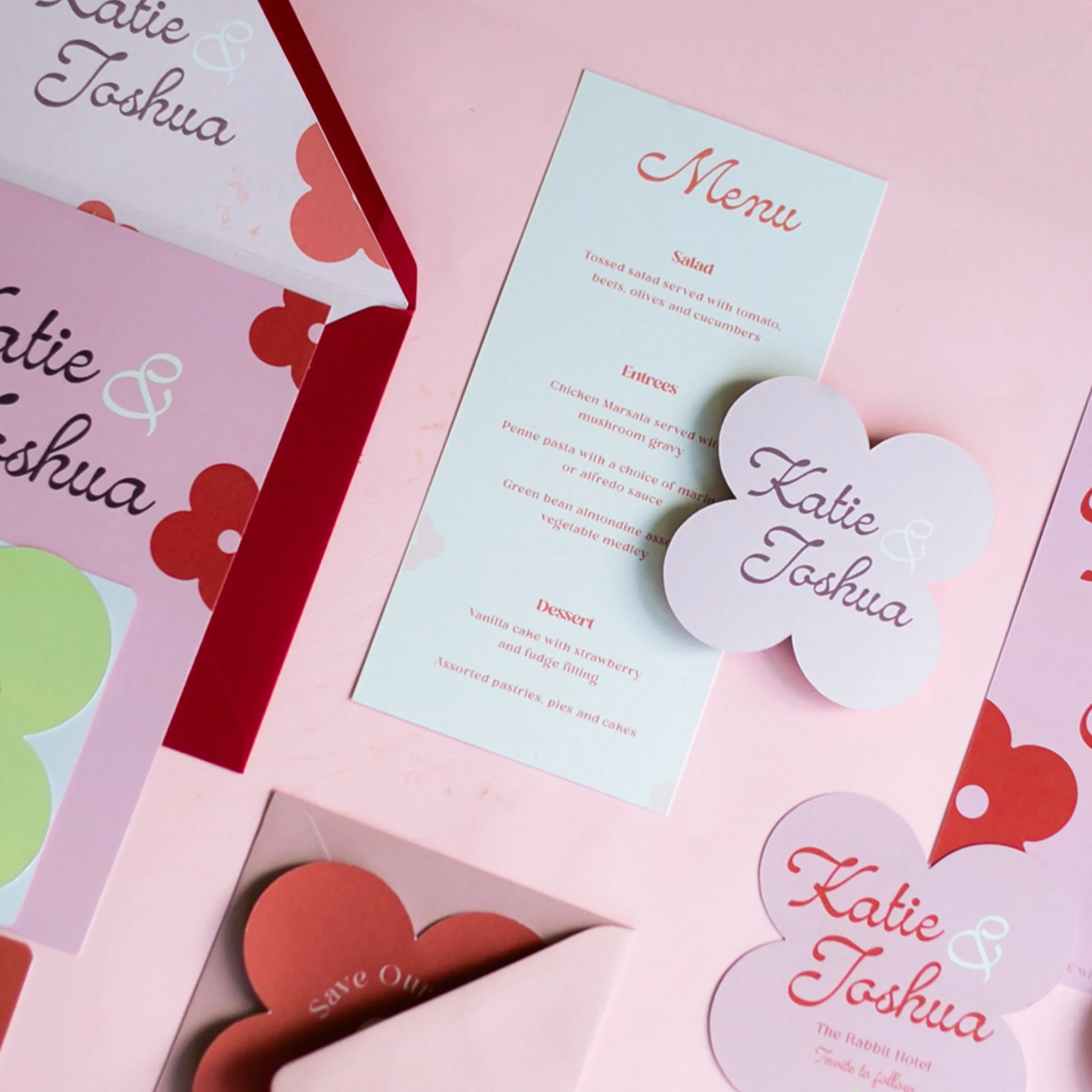 Wedding menu card and decorative paper items for Katie & Joshua with floral and pastel pink designs, including a paper flower with their names.