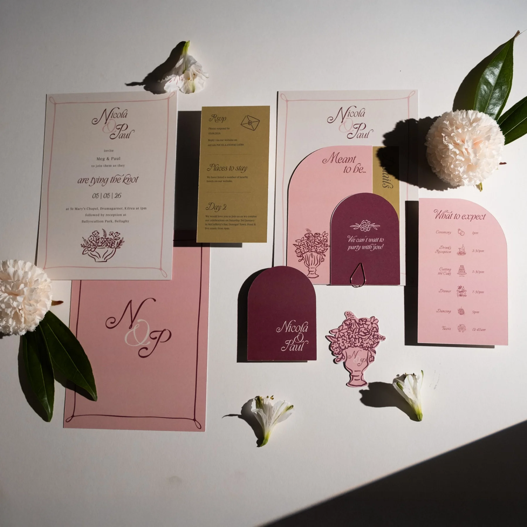 Wedding or event invitation stationery with floral accents and decorative elements, including RSVP card and schedule, arranged on a white background with flowers and leaves.