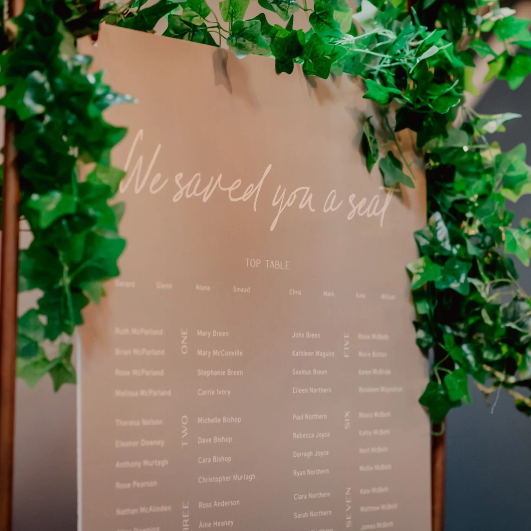 A seating chart decorated with green ivy leaves for a wedding or event.