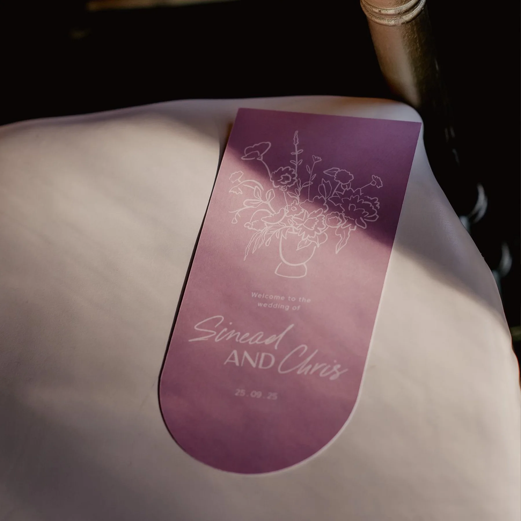 Wedding program or invitation with a purple gradient background, floral design, and text that says "Welcome to the wedding of Sinead and Chris, 25.09.25."
