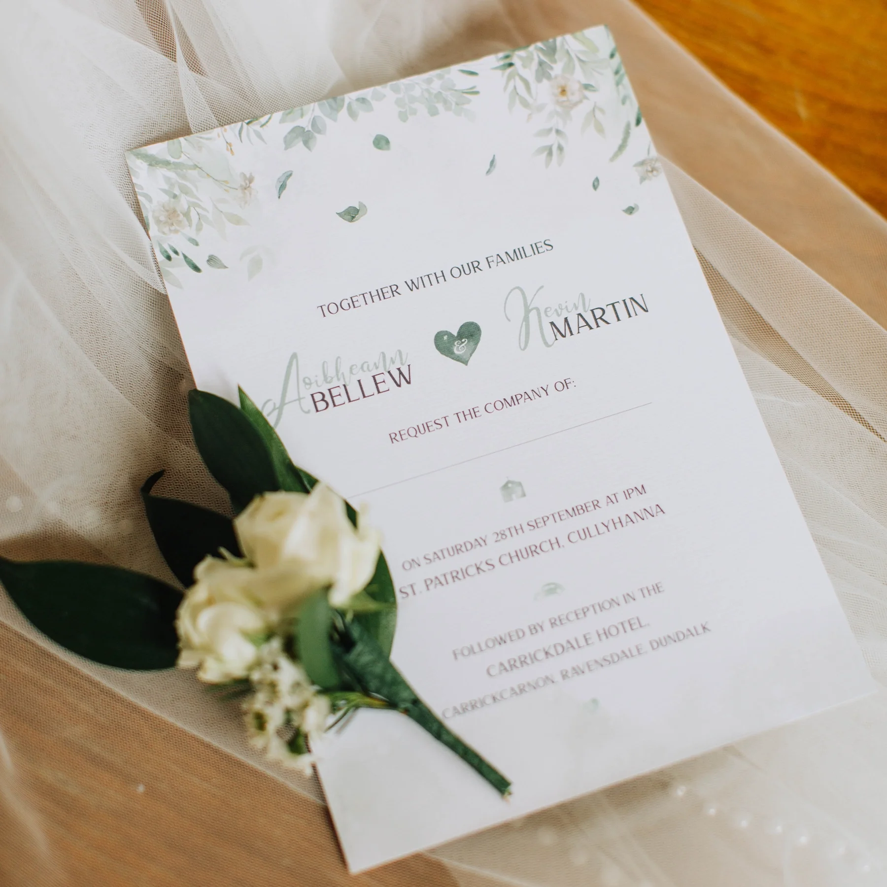 Wedding invitation with floral accents, featuring the names Aoibheann Bellew and Kevin Martin, and details of the ceremony at St. Patrick's Church, Cullyhanna, followed by reception at Carrickdale Hotel.