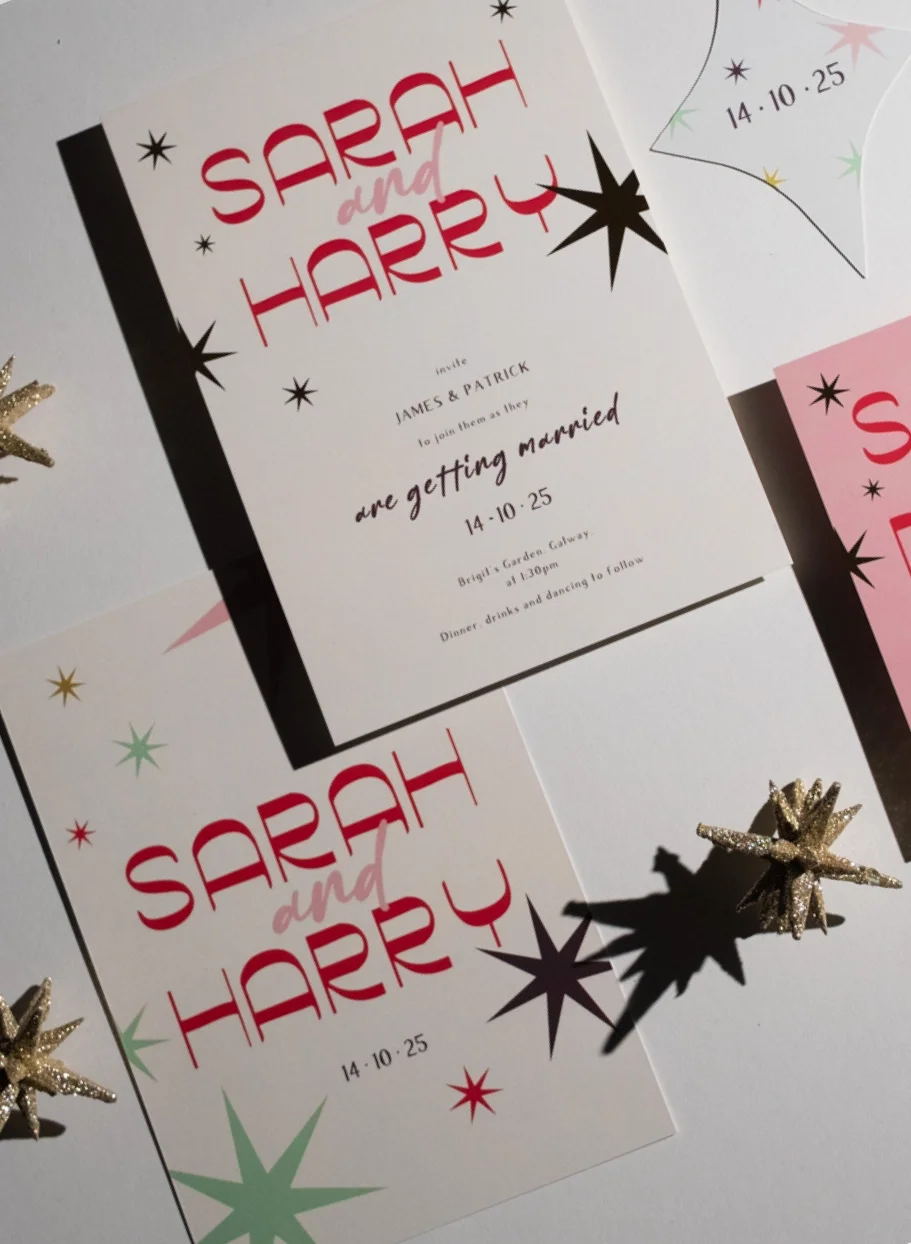 Flat lay of Mid-Century Modern wedding invitation suite featuring red and pink starburst motifs, atomic-age typography, and celestial-themed Save the Date cards for a wedding.