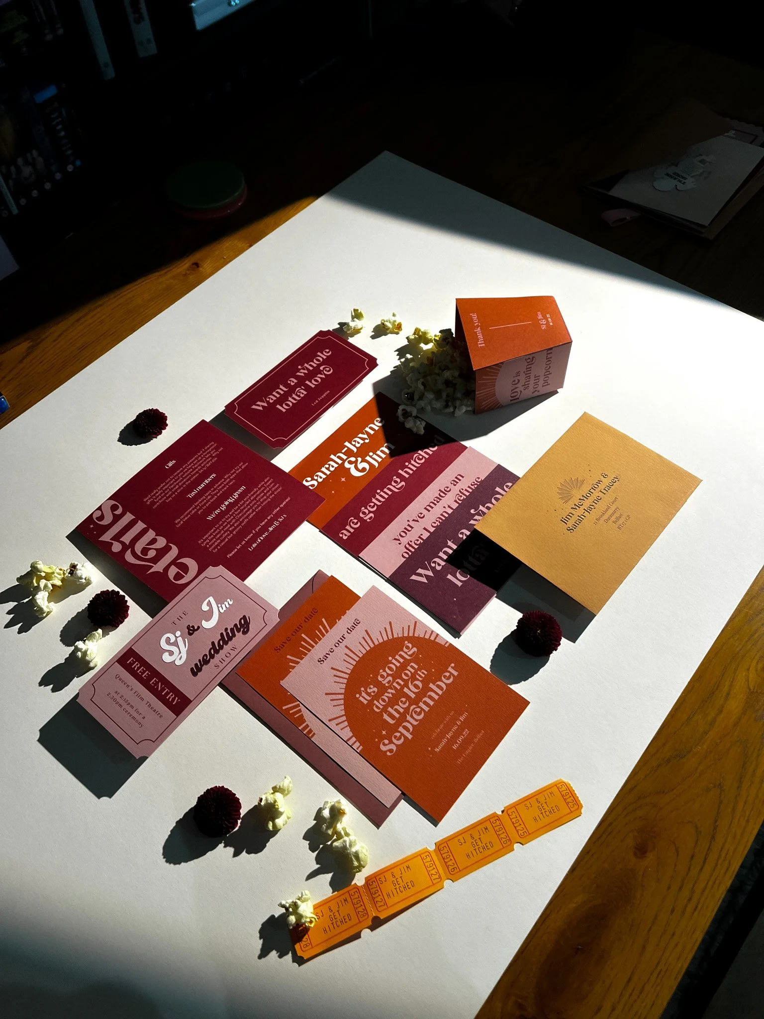 Various wedding invitations, RSVP cards, tickets, and decorative flowers arranged on a white surface.